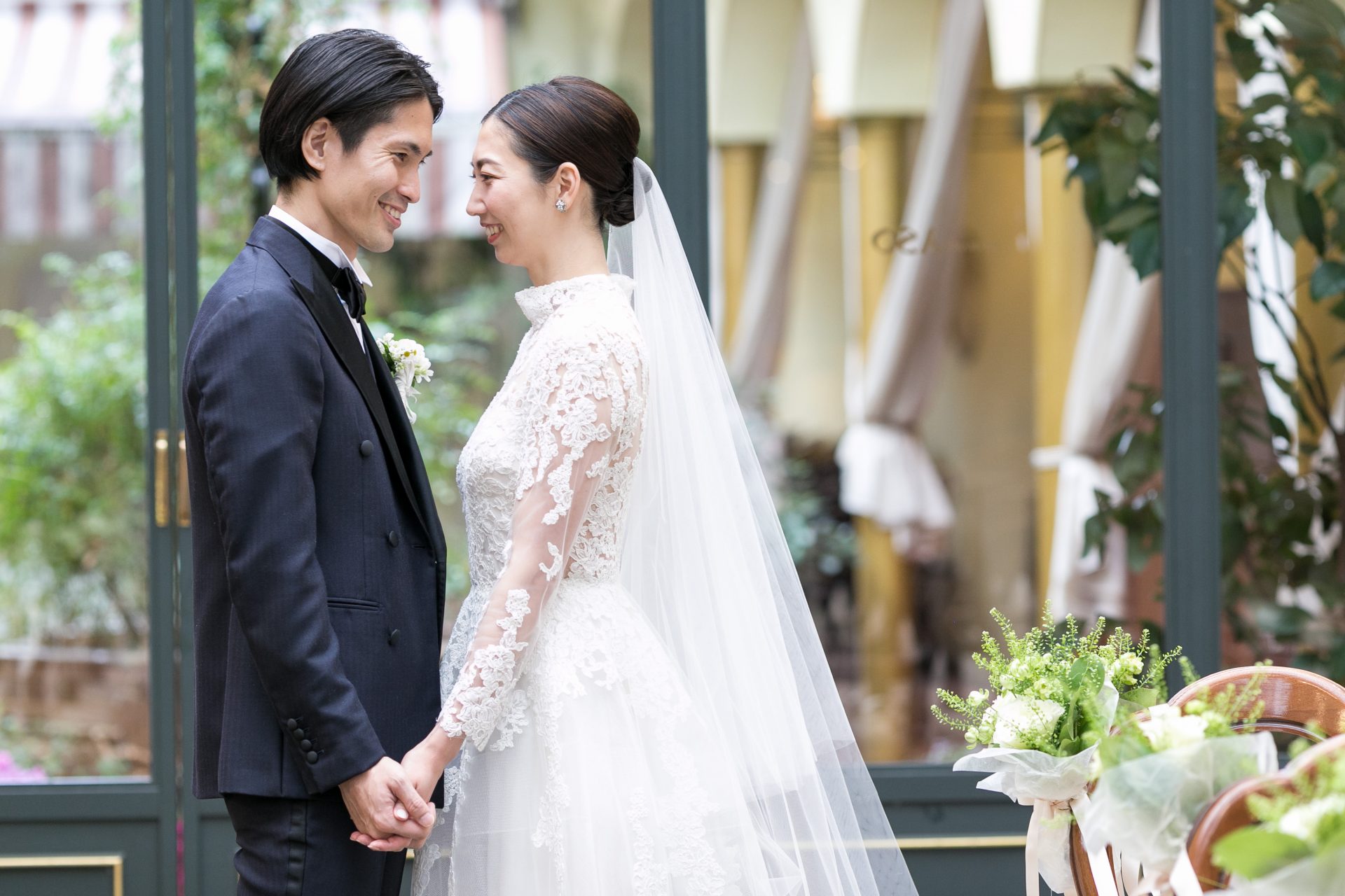 ロングスリーブのウェディングドレスを身に纏うクラシカルな雰囲気のご新婦様とネイビーのダブルボタンタキシードをお召しになったご新郎様がエスコートをするとてもおしゃれな結婚式です