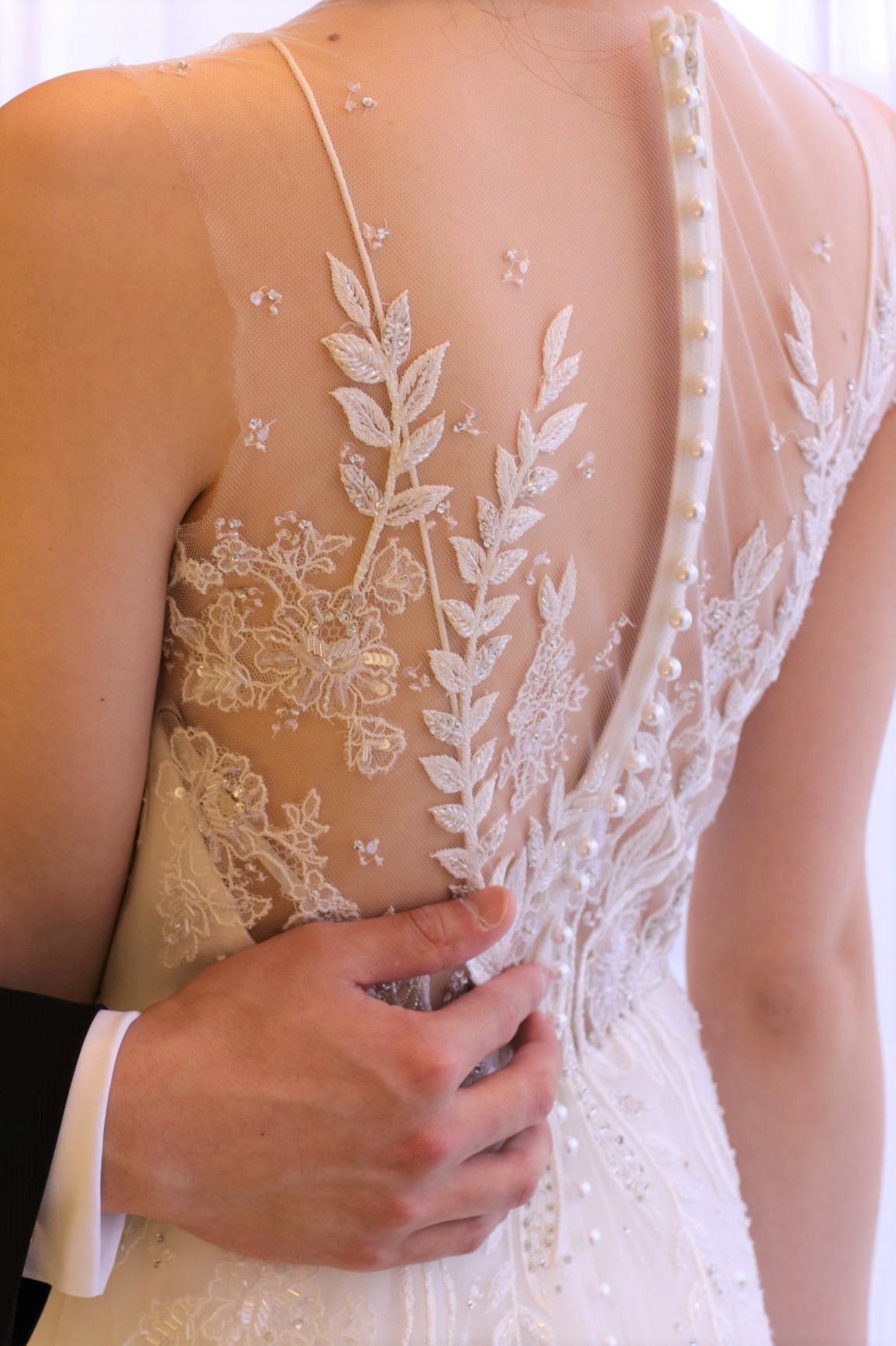 手刺繍によって美しく重なり合うレースやビジューが背中に直接描かれているかのようなイリュージョンレースは、バックスタイルを鮮やかに彩り、前撮りや当日のフォト撮影にも写真映え抜群のデザインです