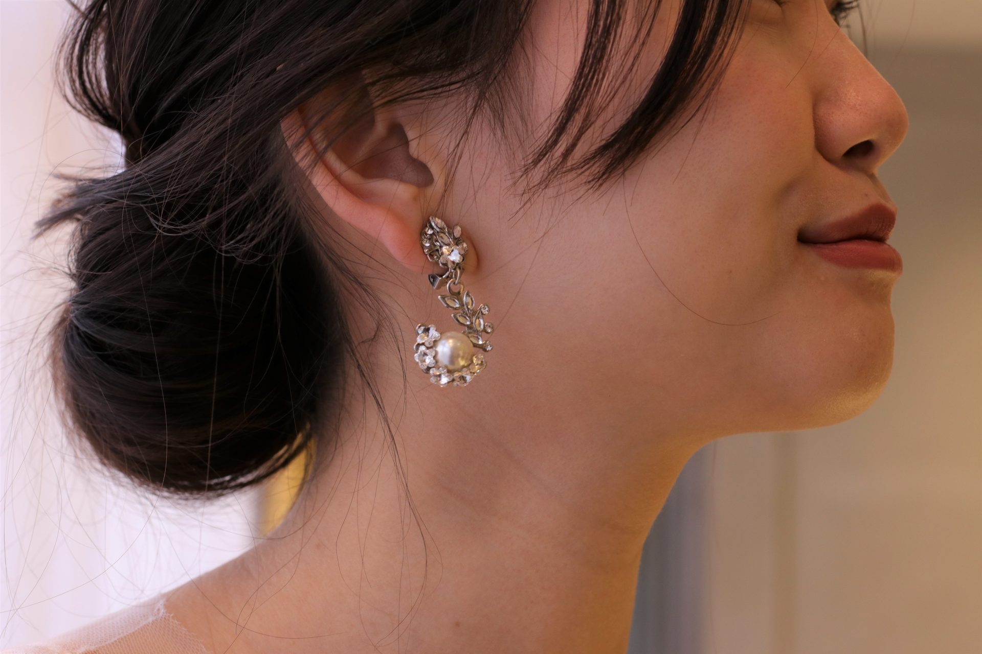 挙式のシーンらしく上品にまとめたシニヨンヘアには、海外のアクセサリーブランドからセレクトをしたパールイヤリングを合わせお洒落なクラシカルスタイルを表現します