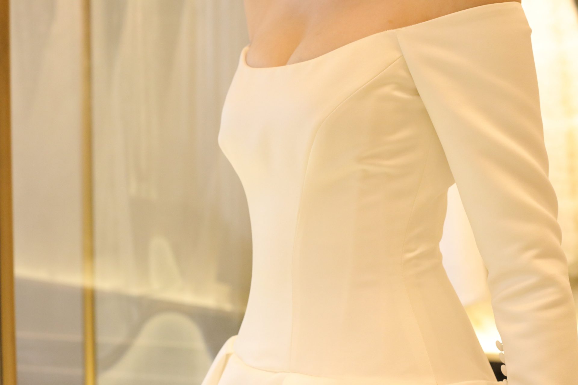 真っ白なシルクサテンの美しい生地で、オフショルダーとロングスリーブが印象的なインポートドレスらしい絶妙なデザインは、高級ホテルウェディングやナイトウェディングにもオススメのウェディングドレスです