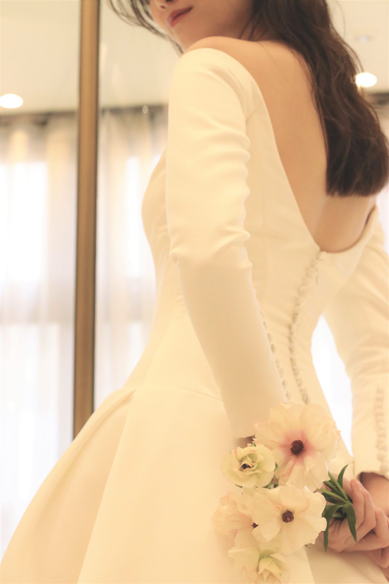 シルクサテンのシンプルなデザインですが、大きくあいた背中のデザインと美しく魅せる綺麗なウエストライン、可愛らしく並ぶクルミボタンが、バックスタイルも印象的で、前撮りや後撮りにもオススメの写真映えするウェディングドレスです