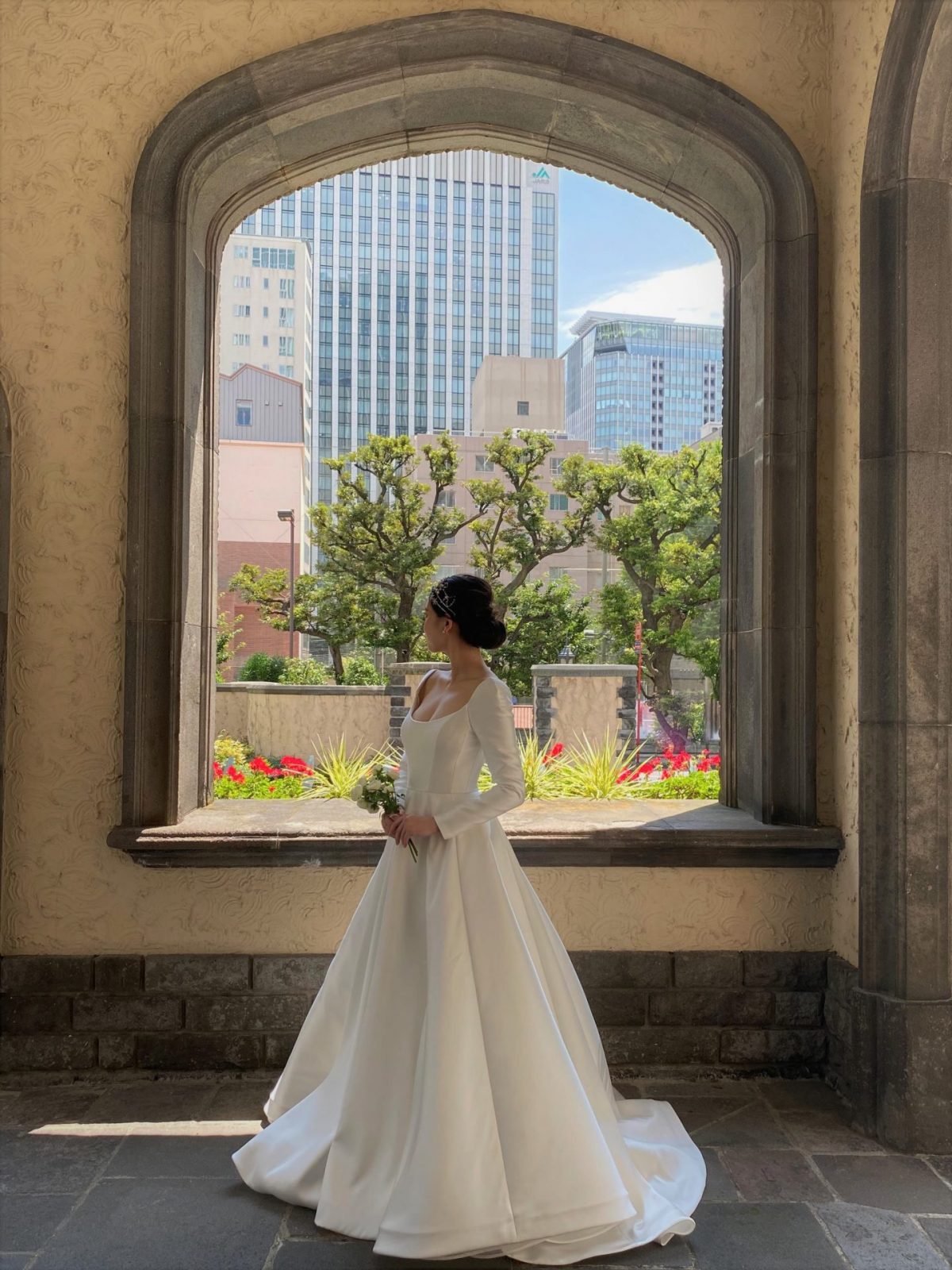 東京の都会の風景と有形文化財の赤坂プリンスクラシックハウスの趣ある建物に、ザ・トリート・ドレッシング アディション店のリームアクラの純白なウェディングドレスがとても映えます