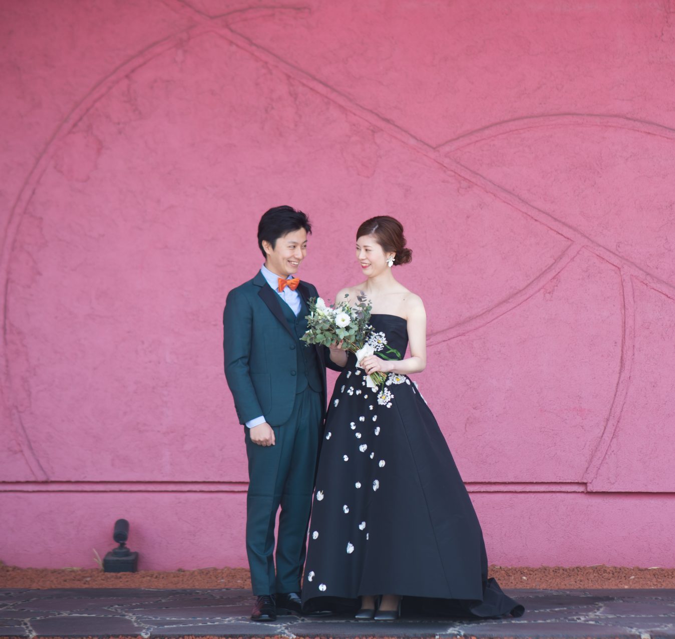 ザ・ルイガンズの赤い壁の前でおしゃれな前撮りが叶う、ザ・トリート・ドレッシングのカラードレス