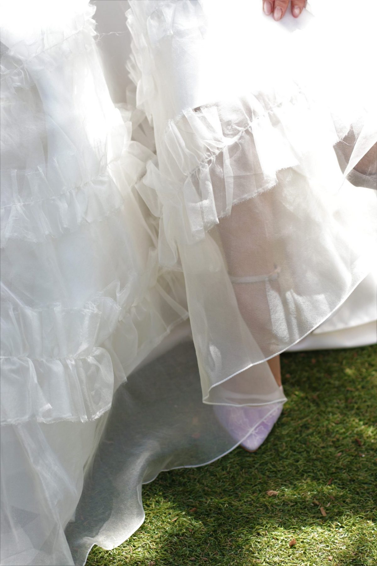 太陽の日差しが差し込むガーデン挙式の花嫁様に、ザ・トリート・ドレッシングのドレスコーディネーターが提案するのは、軽やかなオーガンジー素材のAラインのウェディングドレスにレース素材のブライダルシューズを合わせたコーディネートです