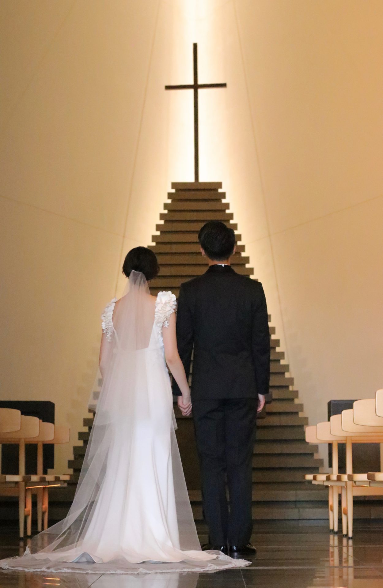 虎の門ヒルズ最上階にそびえるアンダーズ東京のチャペルは天然素材にこだわった神秘的な空間に、スレンダーラインのウェディングドレスにトリート・メゾンのロングベールを合わせて、お洒落で温かみのある挙式のコーディネートにしています