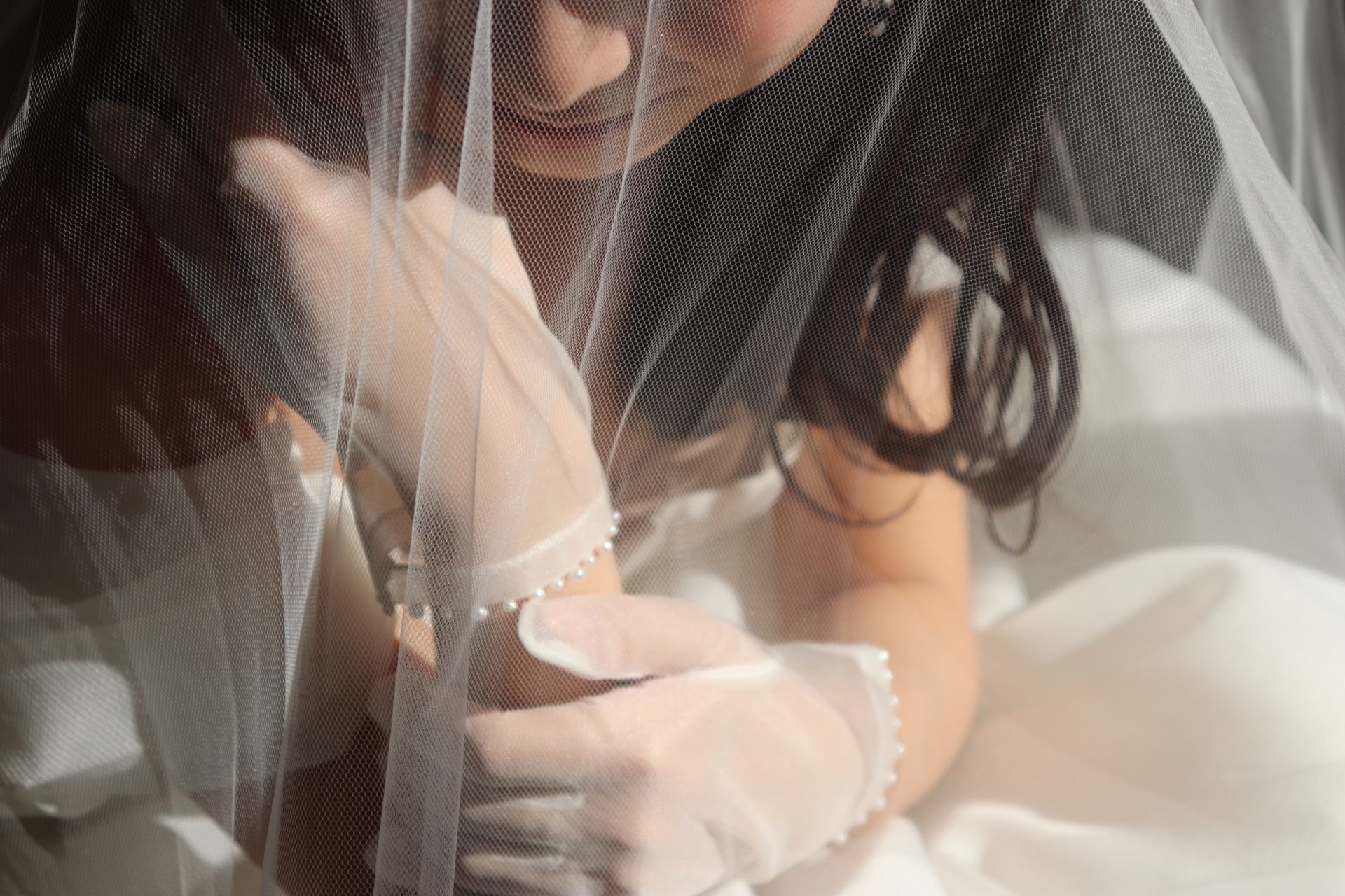 ザ・ガーデンオリエンタル大阪の自然光の差し込むチャペルにてベールとパールのグローブをお召になる花嫁様