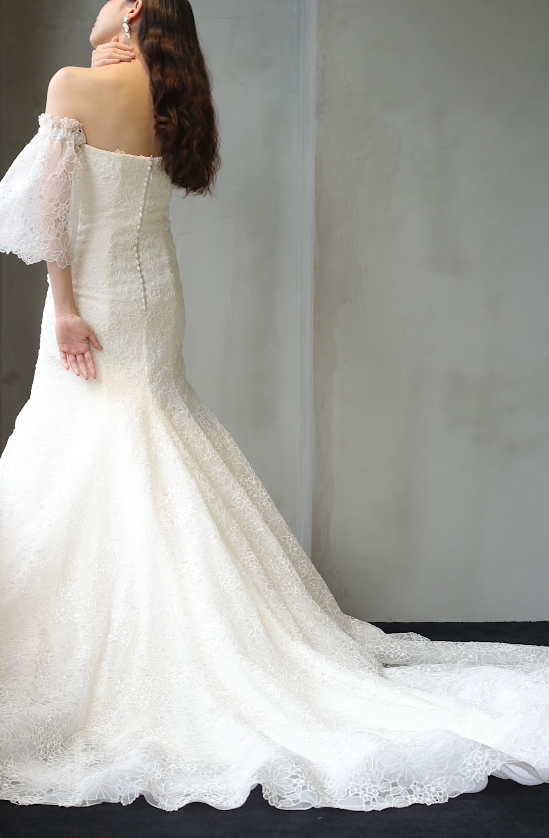 豪華な総レースやくるみボタンのトレーンが長いウェディングドレスは、トレンドのバックコンシャスなデザインなので、チャペルでバージンロードを歩く際や前撮りの螺旋階段での振り向きショットで写真映えします。