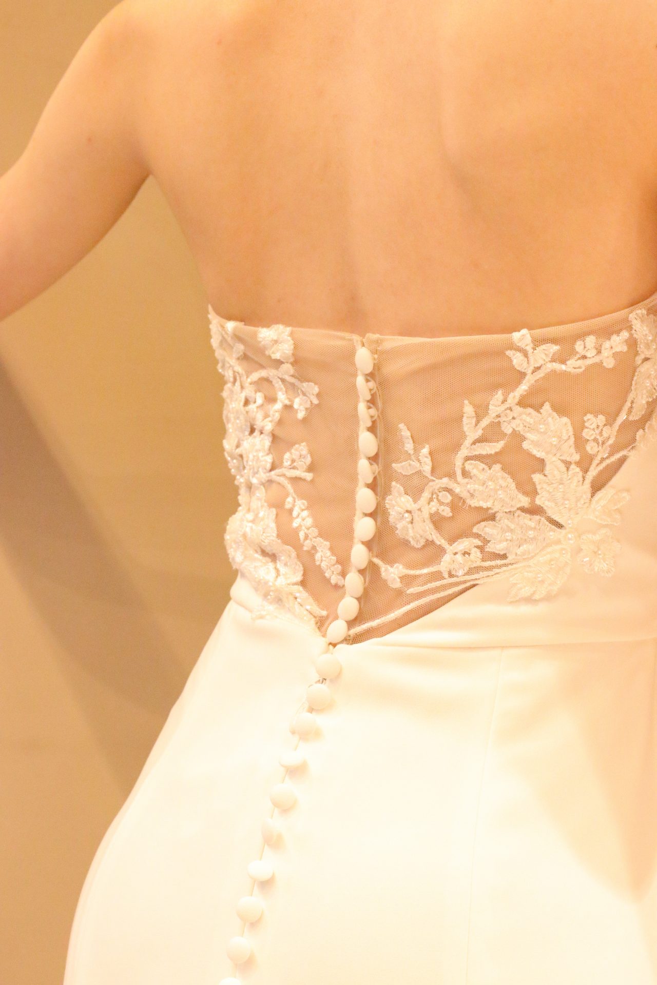 繊細でありながらも立体感のあるレースや、ファスナートップから裾元まで贅沢に連なるくるみボタンは、ご新婦様のバージンロードでの歩みを華やか且つ女性らしく演出します