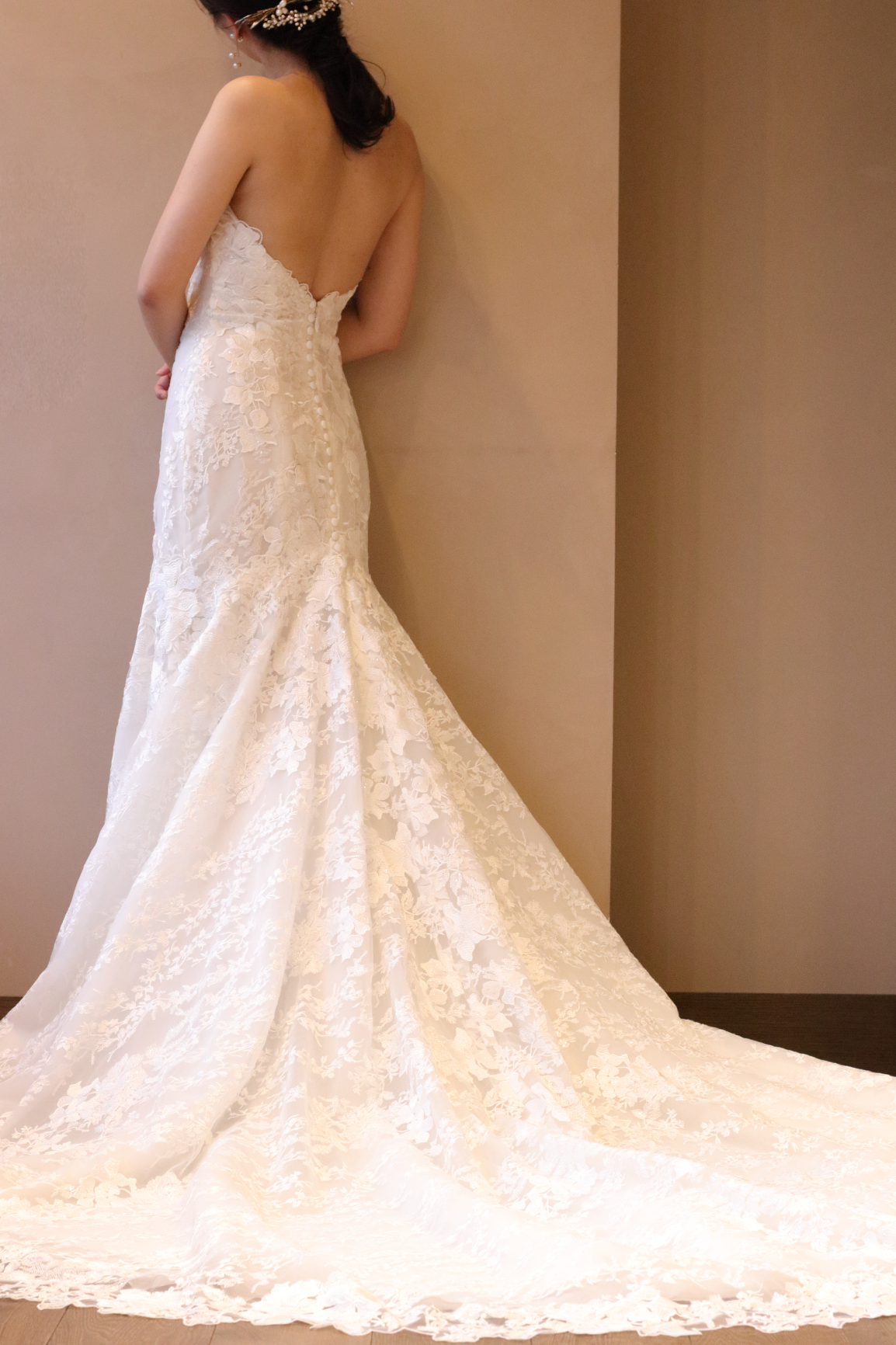 大胆な背中のカッティングが肩甲骨を美しく見せ、レースでデザインされたボリュームあるトレーンと相まって女性らしいバックスタイルを演出します