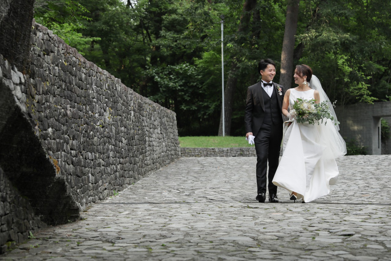 国内リゾートウェディング、軽井沢・石の教会でトリートのオスカーデラレンタのウェディングドレスをお召しになられたご新婦様とご新郎様が向き合う様子。