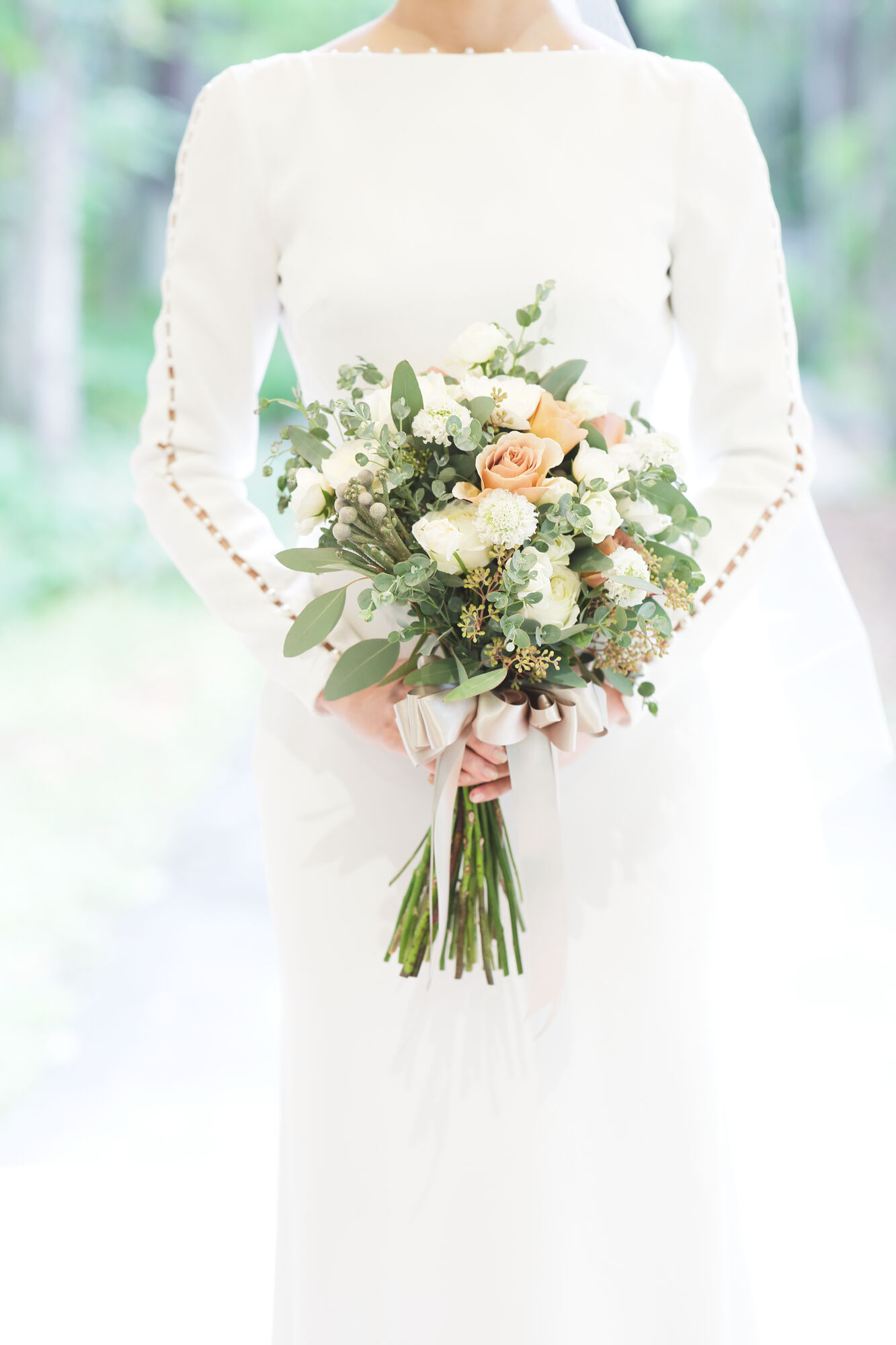 リゾートウェディングを叶える軽井沢にぴったりのブーケをもち、クレープ素材のロングスリーブウェディングドレスを着たご新婦様。