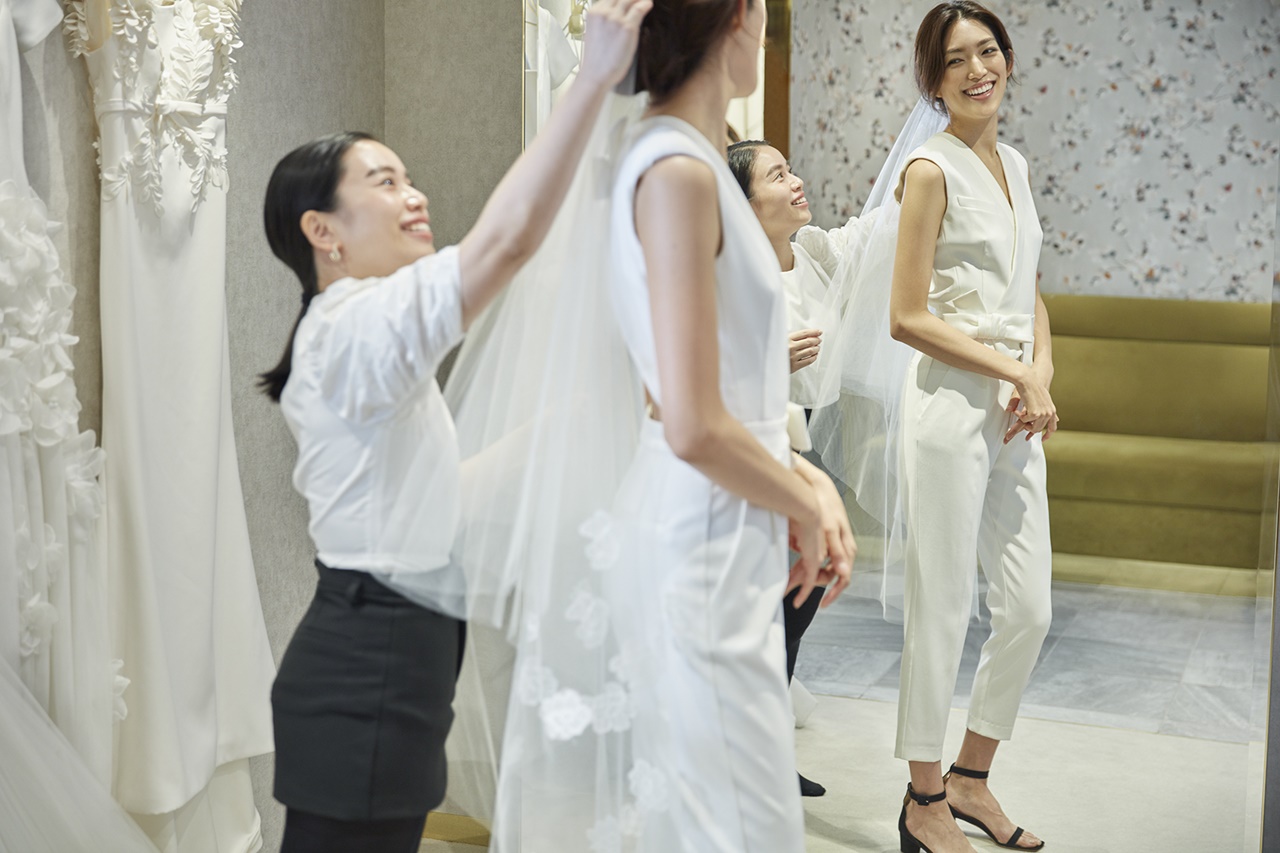 パンツスタイルのヴィクター&ロルフ・マリアージュのウェディングドレスにトリート・メゾン・エ・アトリエのウェディングベールを合わせた望月芹名さんとご案内をするPR飯島智子