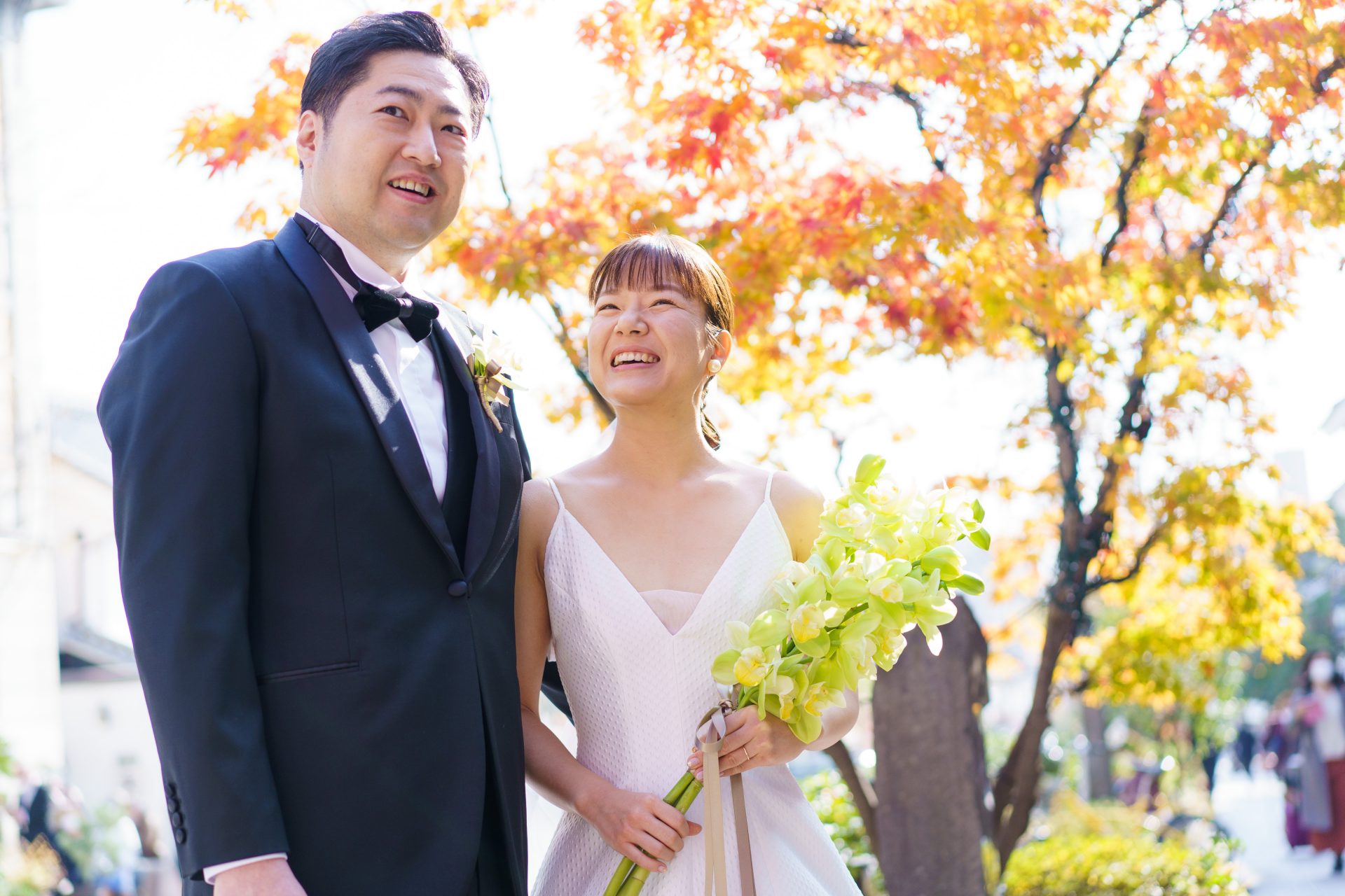 美しい紅葉の中でTHE TREAT DRESSINGのブラックフォーマルのタキシードとAラインのウェディングドレスを身に纏うご新郎様ご新婦様