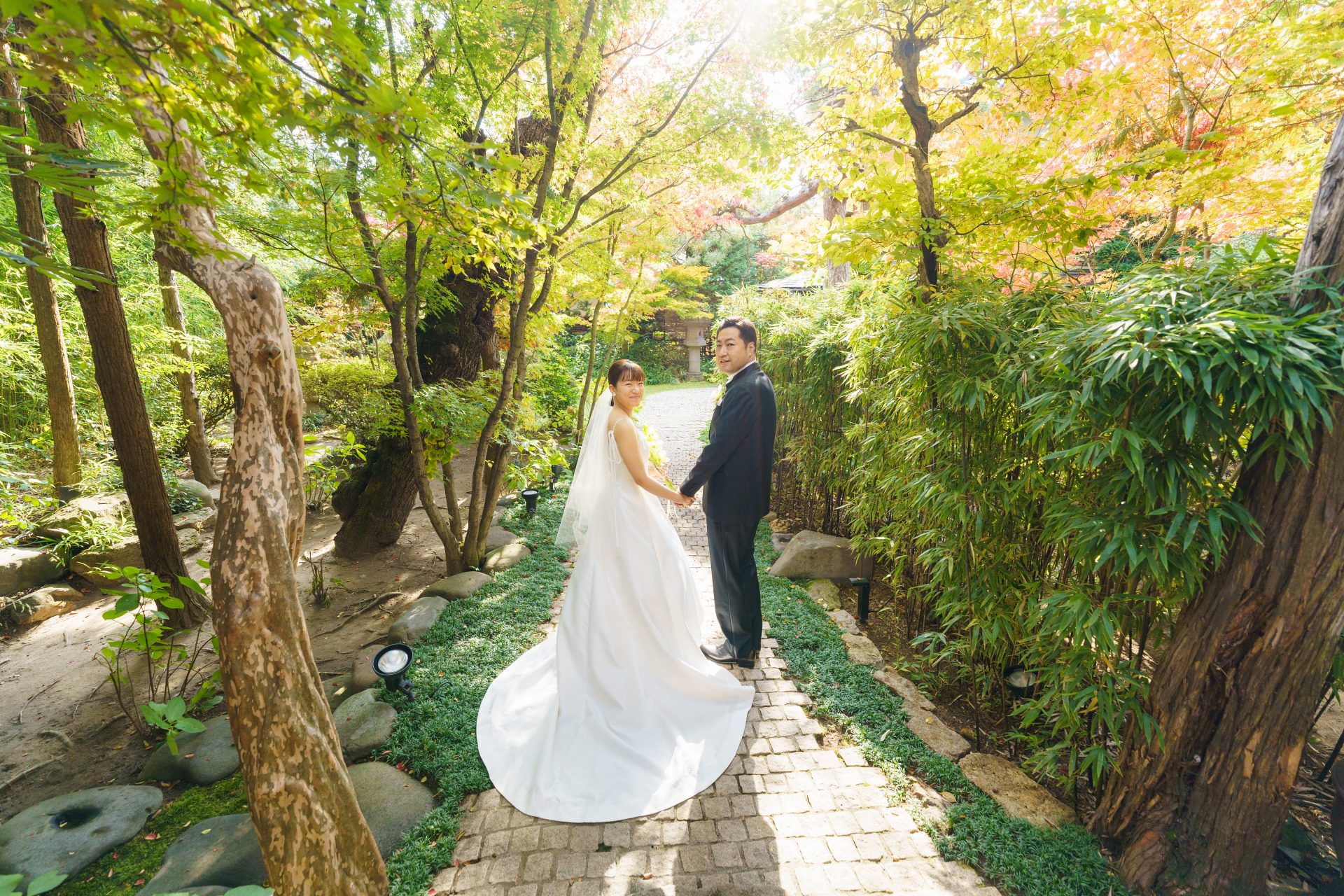 藤屋御本陣チャペル前でTHE TREAT DRESSINGのブラックフォーマルのタキシードとAラインのウェディングドレスを身に纏いこちらを幸せそうに振り返り微笑むご新郎様ご新婦様