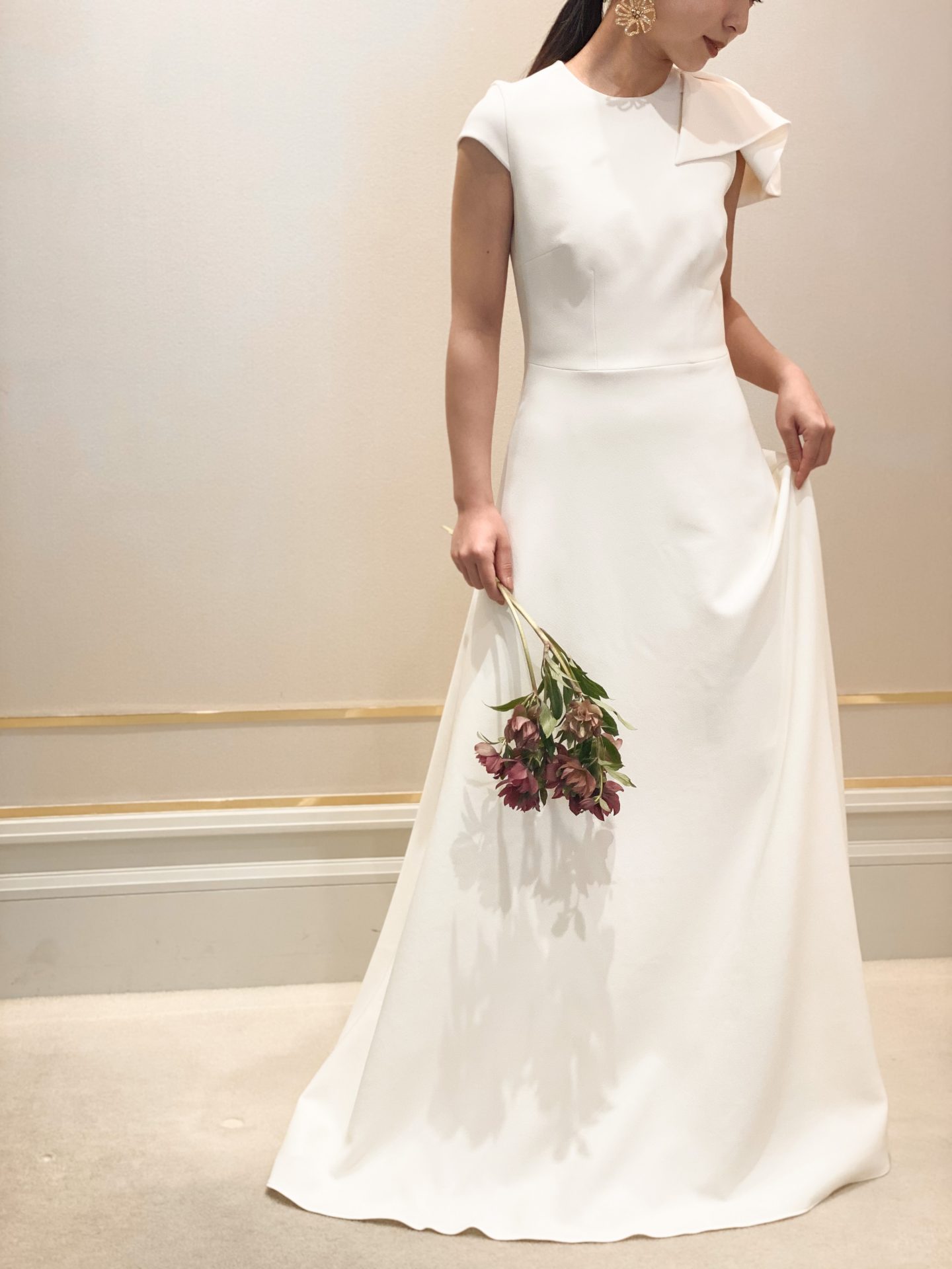 滑らかなでとろみのあるクレープ生地のAラインのウェディングドレスにはゴールドのアクセサリーとダークカラーのブーケをコーディネートすることでモードな雰囲気に