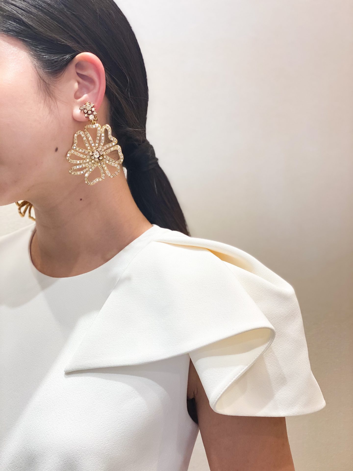 モードでスタイリッシュな雰囲気のウェディングドレスに合わせてヘアスタイルはシンプルにまとめたタイトなポニーテールを、大振りのオスカーデラレンタのゴールドのお花のイヤリングを合わせてクールで凛とした女性像を演出