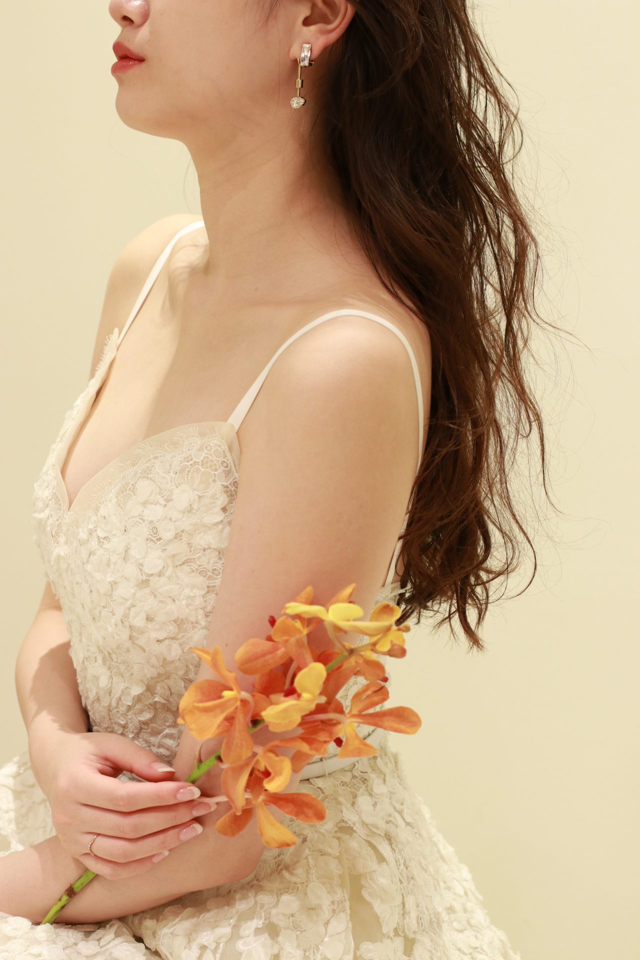 エリサーブの新作ウエディングドレスは立体的なお花モチーフが胸元に施された愛らしい印象なので、すっきりしたモードなイヤリングとダウンヘアを合わせれば大人花嫁におすすめしたいコーディネートに仕上がります