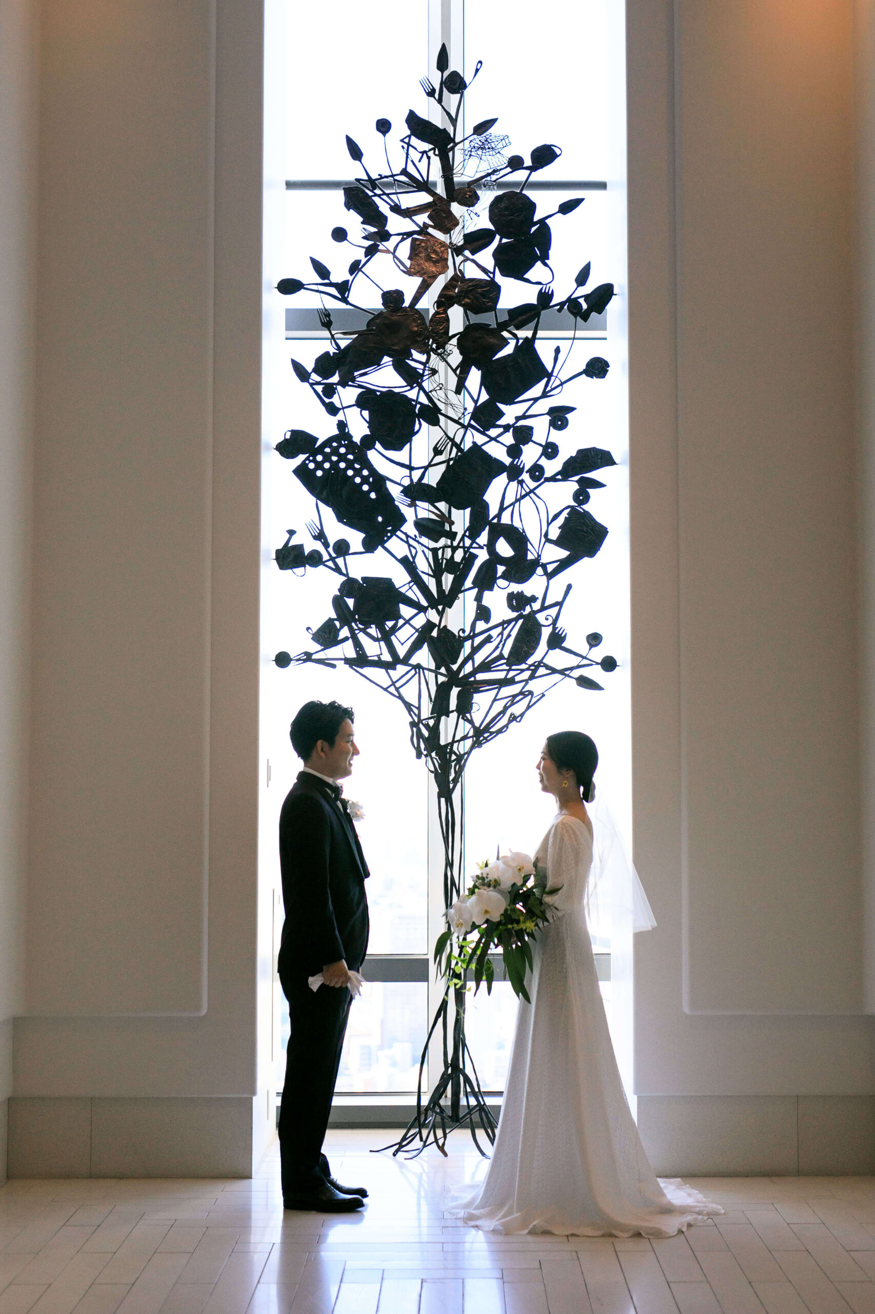 アンダーズ東京のシンボルツリーの前でシンプルなスレンダーラインのサフィアのウェディングドレスとネイビーのタキシードで撮影をされたご新郎ご新婦様