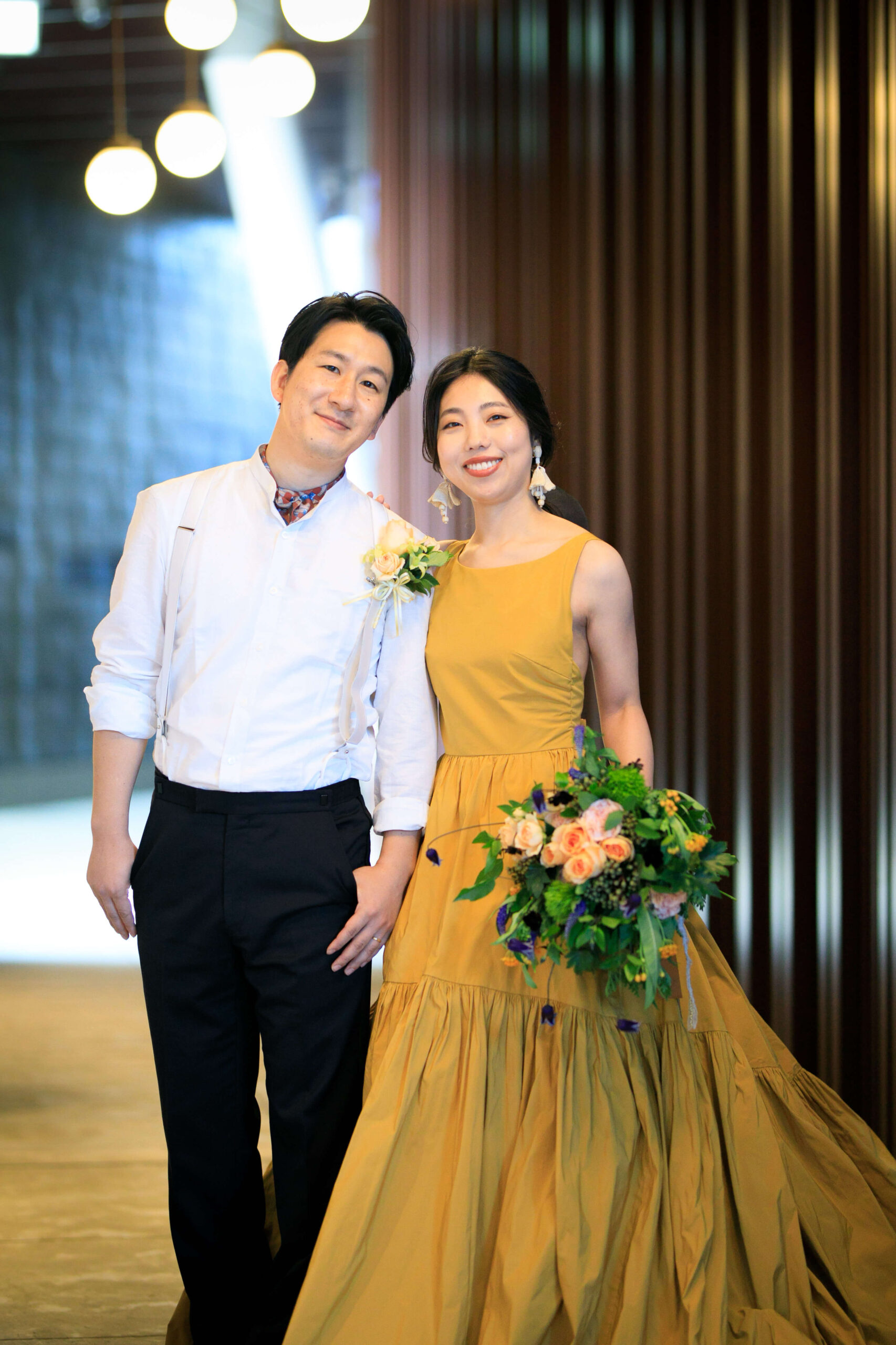 アンダーズ東京の提携ドレスショップザトリートドレッシングアディション店で人気のトリートメゾンのイエローのカラードレスとネイビーのタキシードをファッショナブルにコーディネートされたご新郎ご新婦様