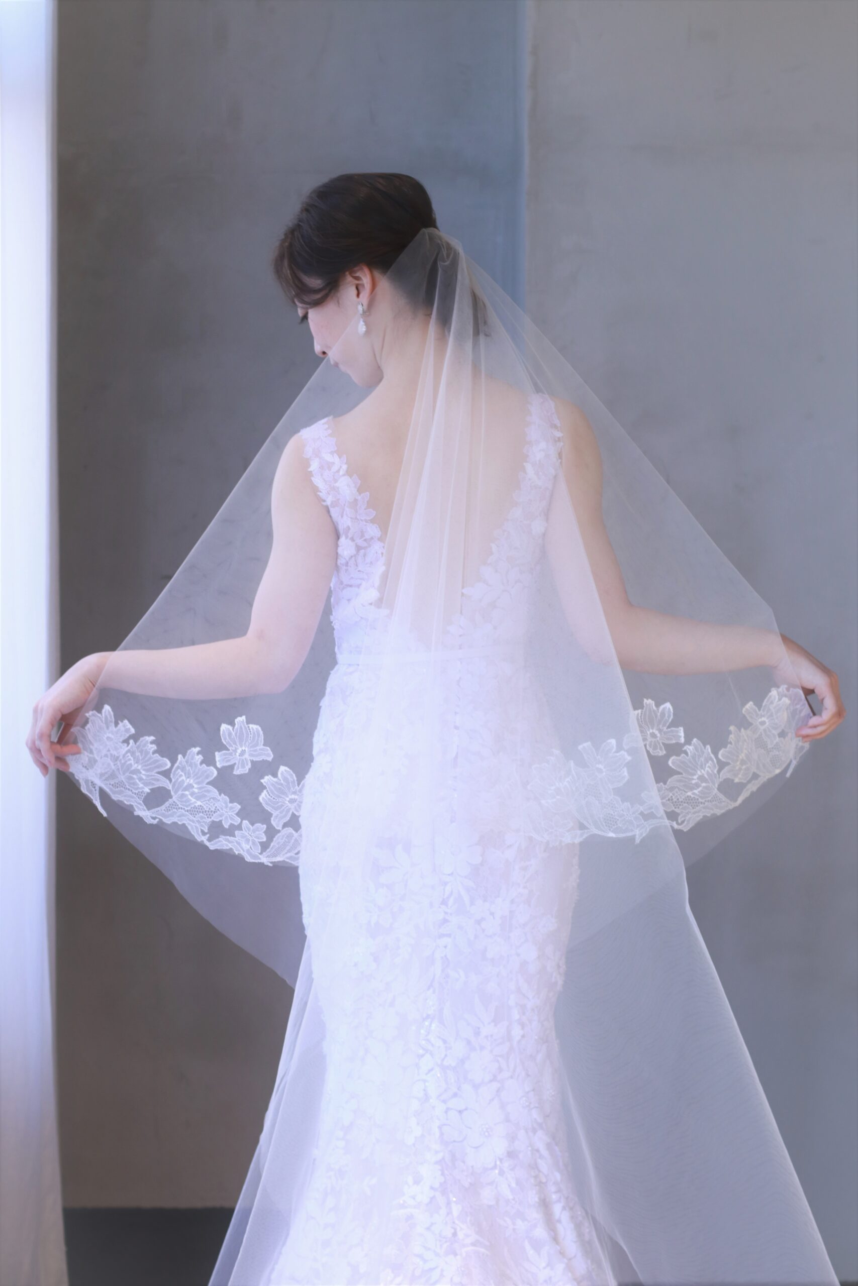 チューリップとコスモスのレースを使用したトリートメゾンオリジナルのベールは、柔らかさと透明感を花嫁にプラスし、ミラズウィリンガーの新作ウェディングドレスのマーメイドラインのシルエットと装飾美を引き立てます