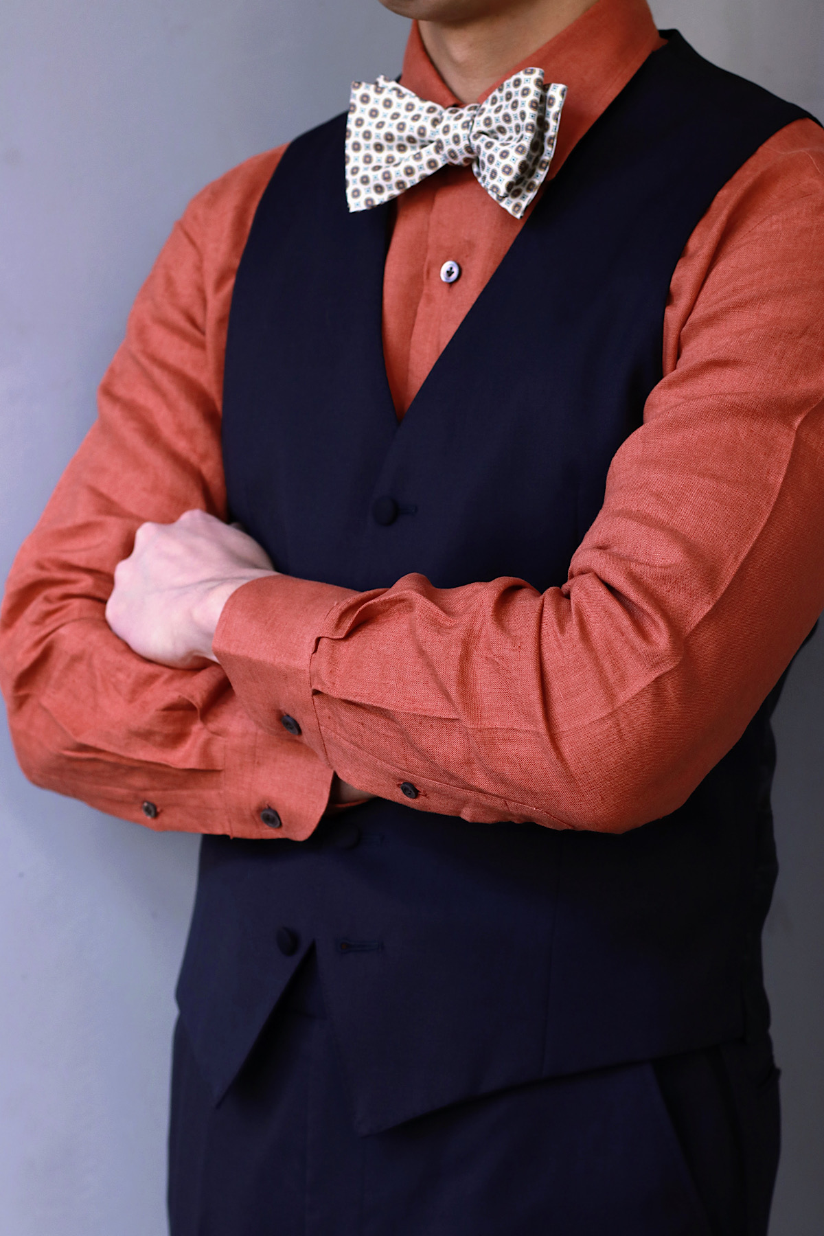 正統なミッドナイトブルーのタキシードを見に纏い、鮮やかなオレンジのシャツをチョイスしたクラシックモダンなコーディネート