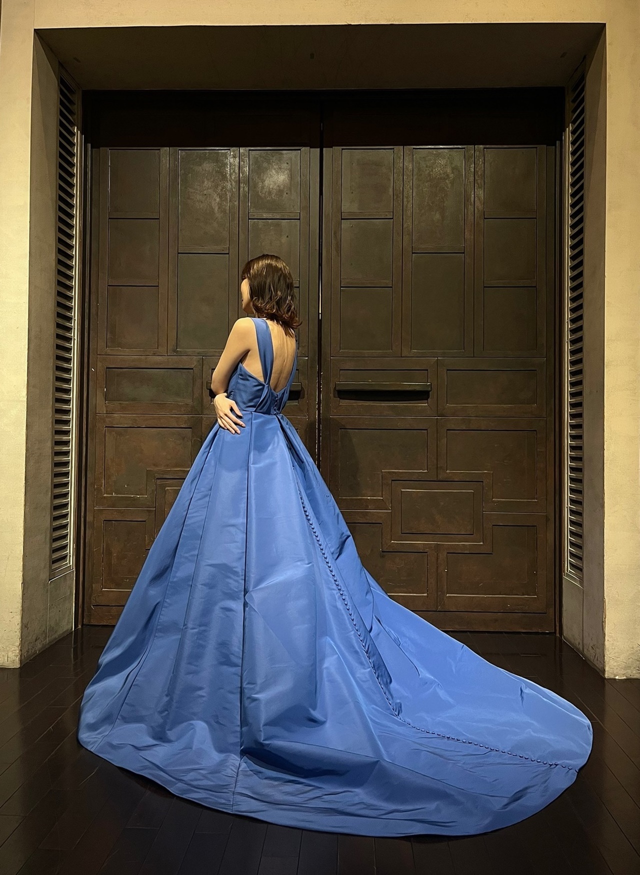 シンプルなハリのあるAラインのカラードレスは、背中のデザインやロングトレーン、くるみボタンがポイント