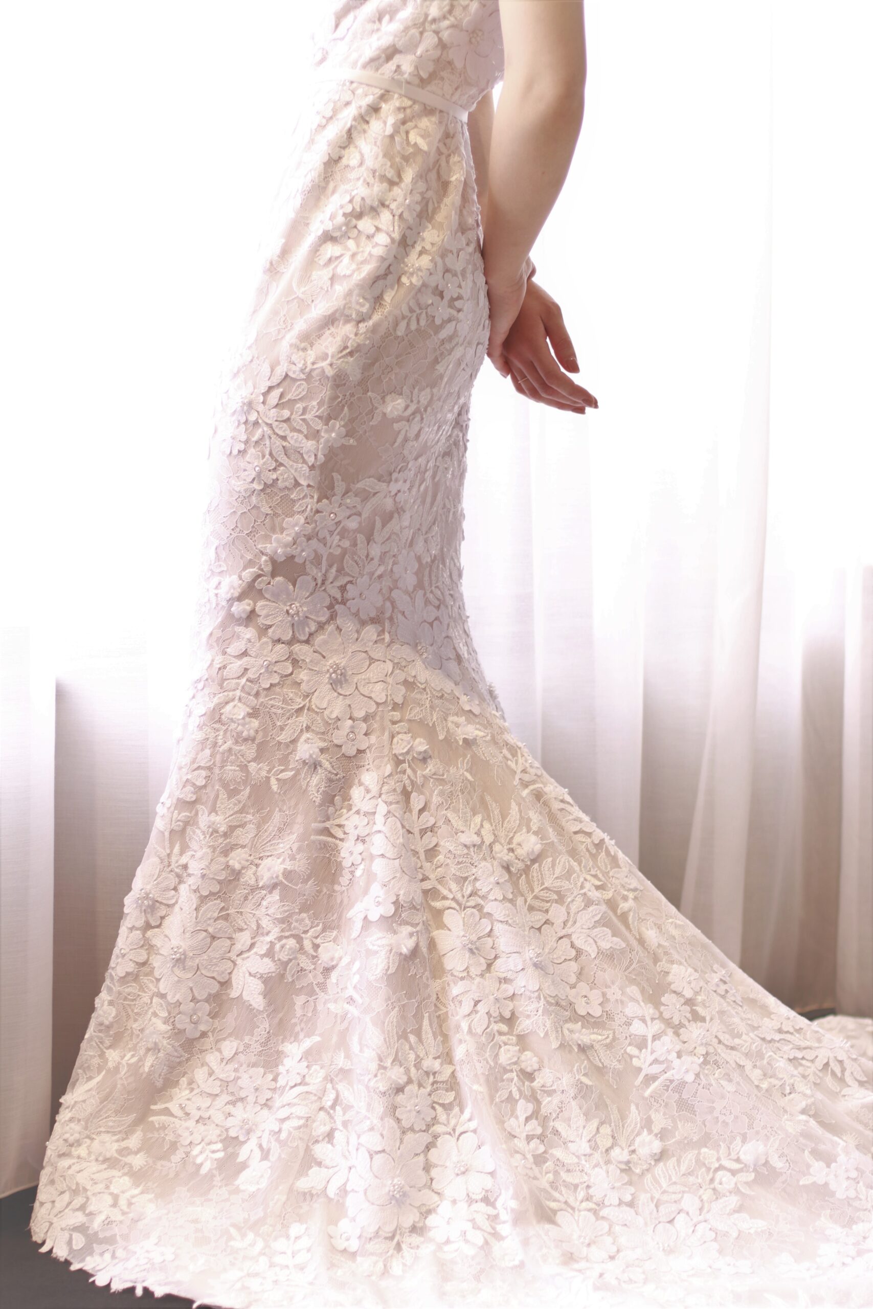 東京の人気結婚式会場、赤坂プリンスクラシックハウスでのご結婚式を予定されている花嫁様におススメの新作ウェディングドレスは、裾元に広がるレースは赤絨毯の上に広がり、立体感のあるアップリケに、繊細に輝くビジューが印象的なマーメイドラインのデザインです