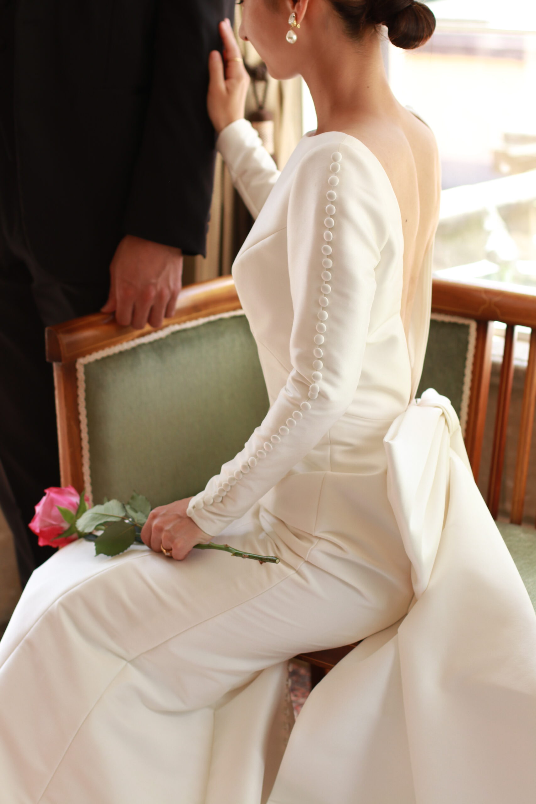 ヴィクターアンドロルフマリアージュのロングスリーブのウェディングドレスの袖には、丁寧に生地で包まれたくるみボタンが並んでおり、花嫁らしい愛らしい印象をプラスします。クラシックなデザインのドレスを引き立てるために髪型はタイトにまとめて、パールのイヤリングでスタイリングしました。