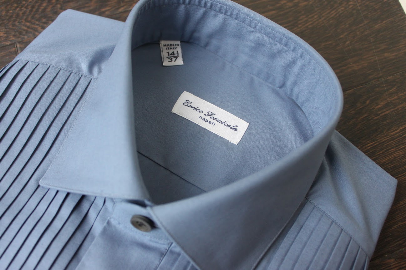 エリコフォルミコラのブルーシャツ。胸元にはプリーツを施したクラシカルなディティールで深みのあるサックスブルー。