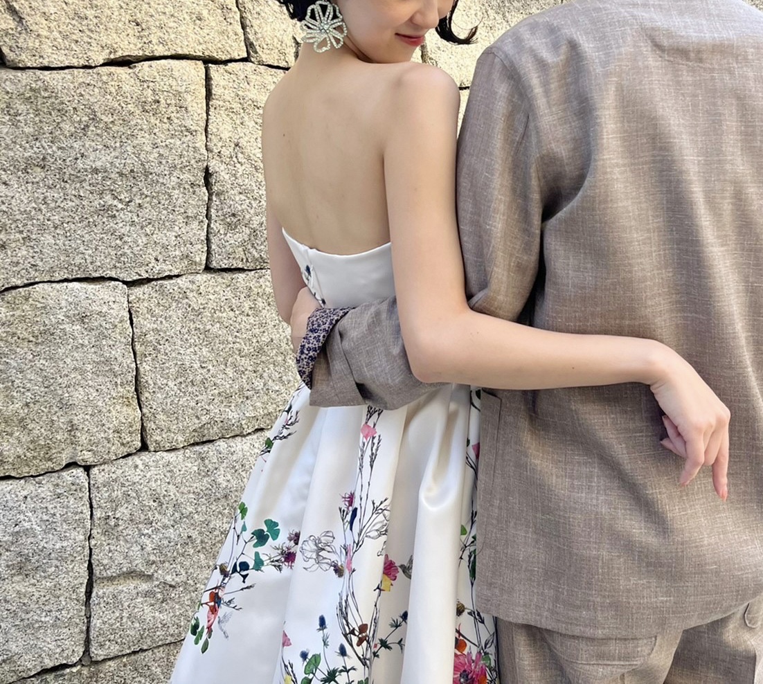 ザトリートドレッシングが神戸エリアにおすすめする、おしゃれ花嫁に人気なモニークルイリエの白地に花柄プリントされたカラードレスとカジュアルなタキシード