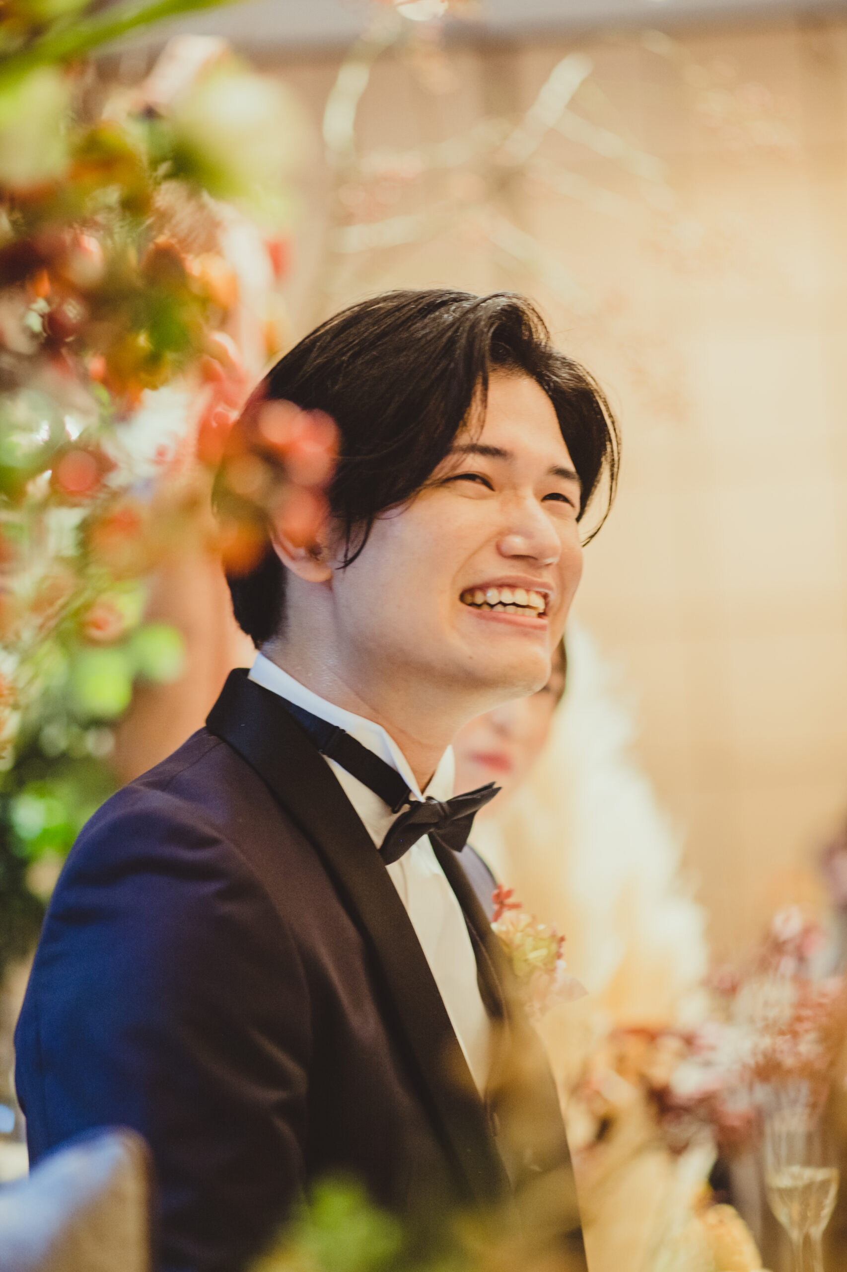 秋らしいカラーの装花に囲まれ、正統派かつアットホームな雰囲気になるネイビーのタキシードを身に纏うご新郎様