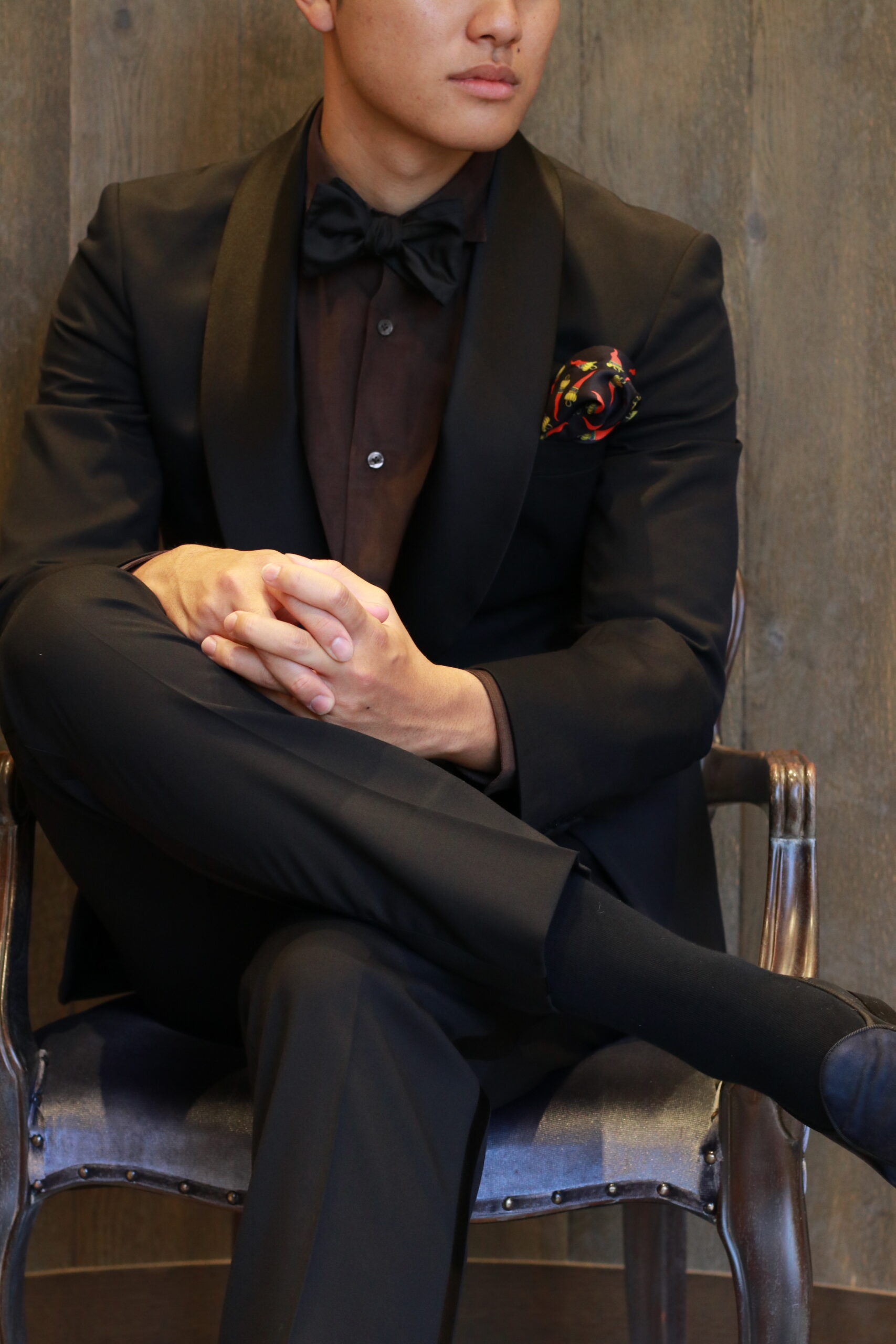 トリートドレッシングのブラックタキシードを身に纏うご新郎様の胸元には、上質なサテンと赤の差し色が洗練された新作チーフを合わせています、