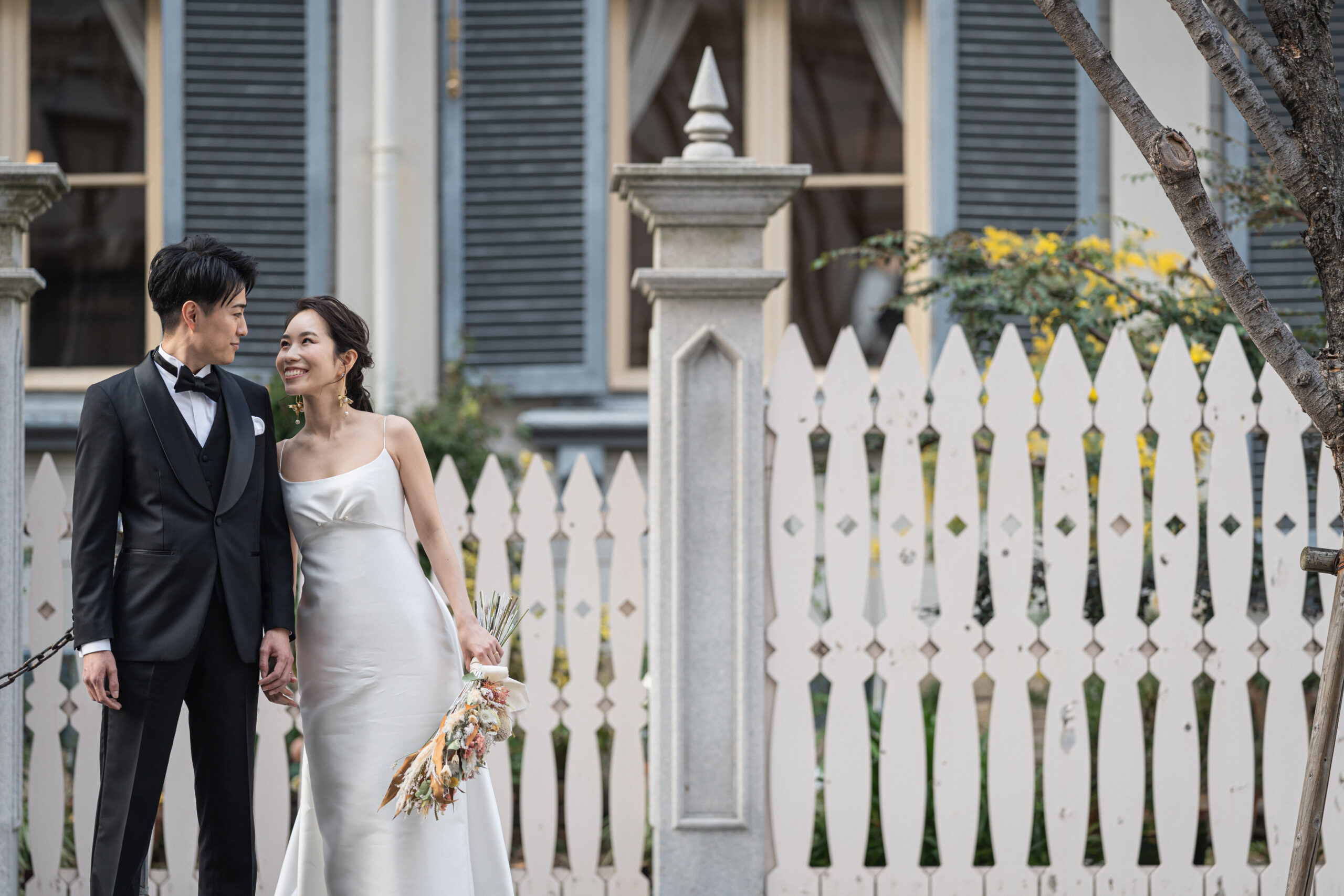 トリートのリラックス感のあるウエディングドレスとブラックタキシードでオリエンタルホテル神戸を背景に居留地の美しい街並みを歩くご新郎様とご新婦様