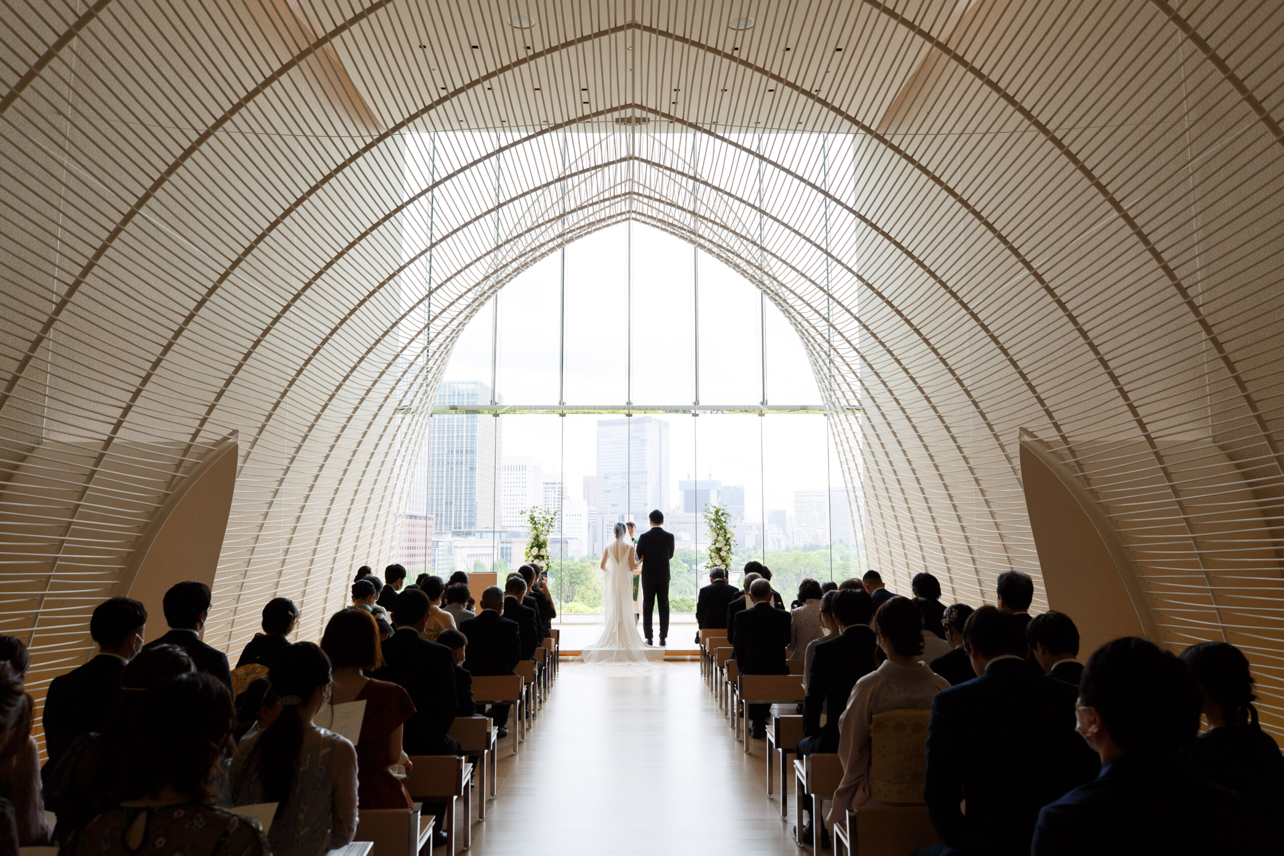 ブラックのタキシード姿のご新郎様とスレンダーラインの美しいシルエットのウェディングドレス姿のご新婦様。