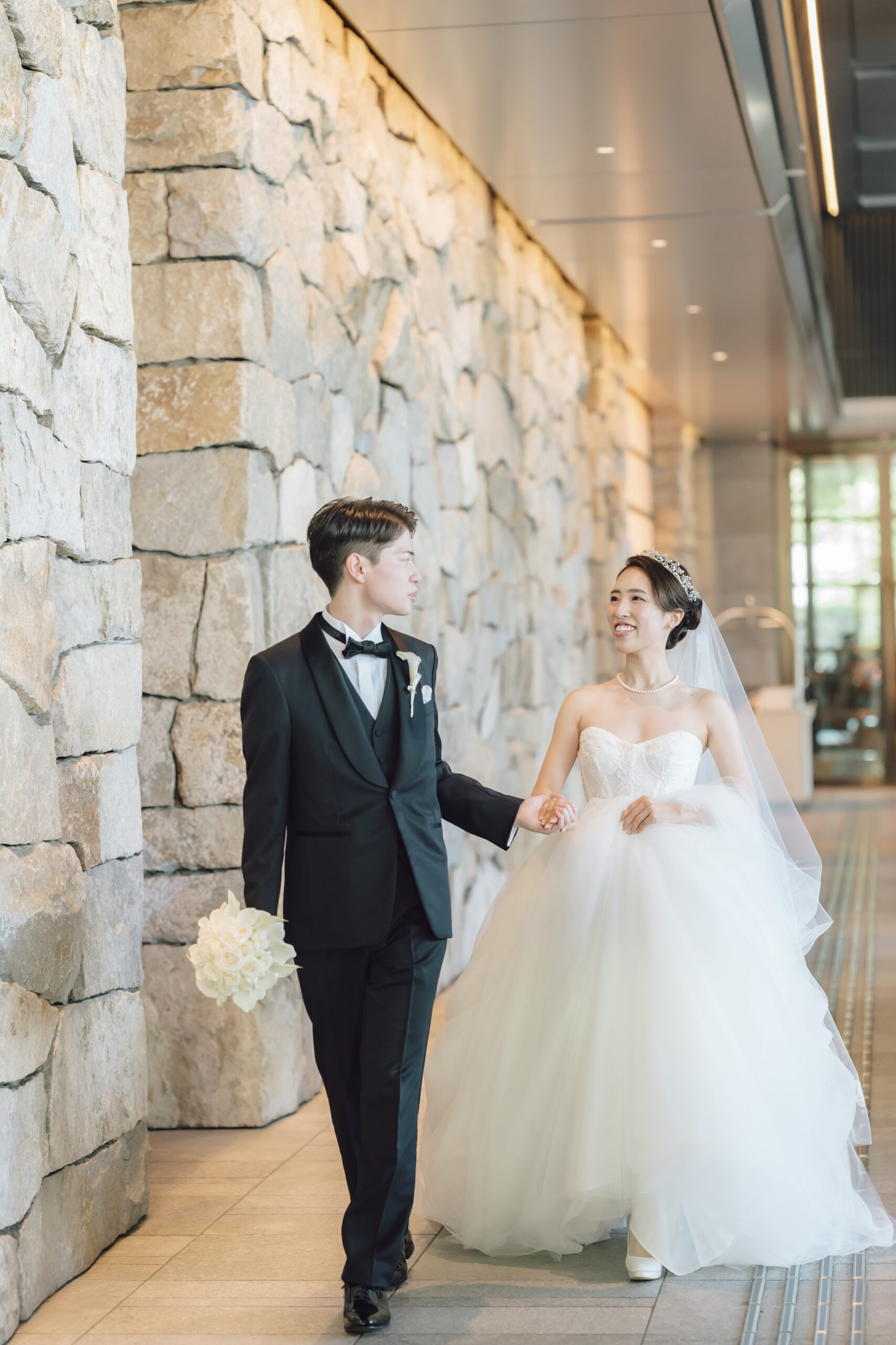 トリートオリジナルのブラックタキシードに身を包むご新郎様とザとリーチドレッシングのみでお取り扱いのあるモニークルイリエのプリンセスラインのチュールドレスを纏うご新婦様