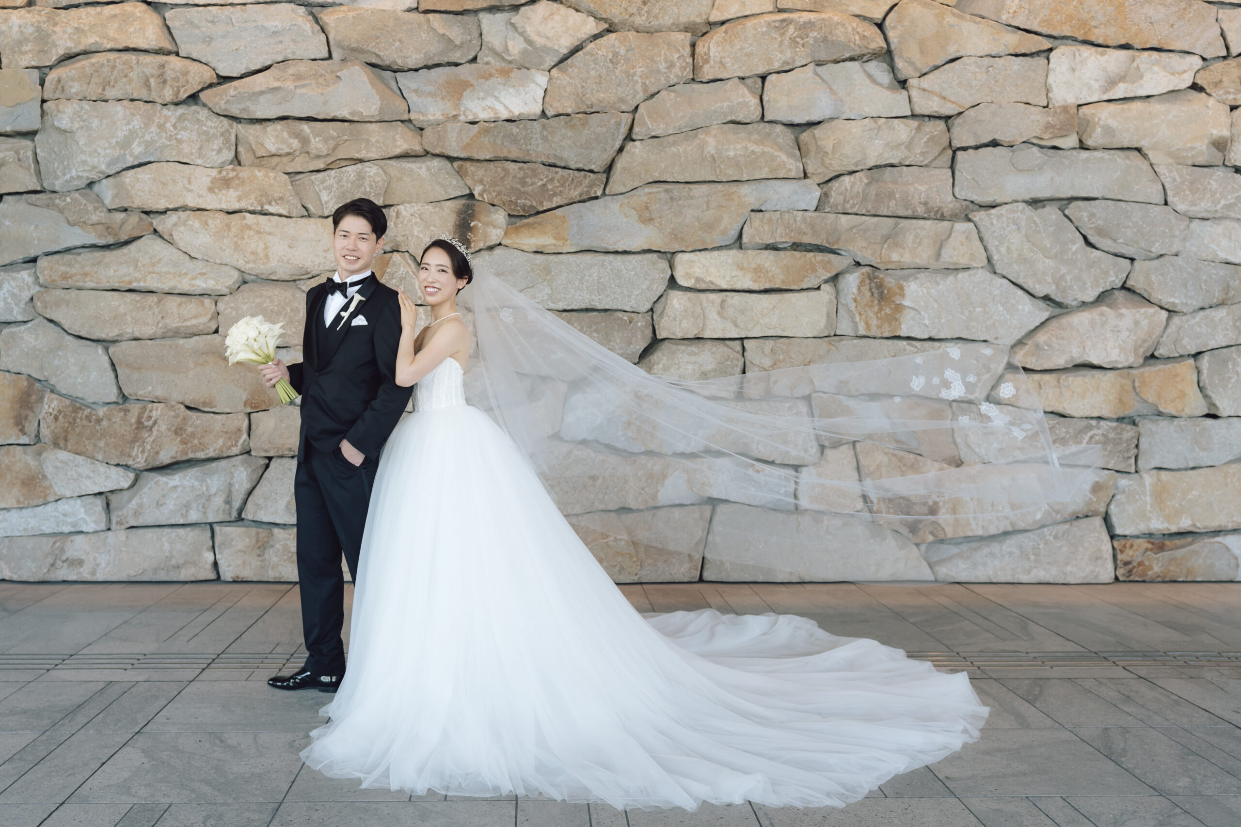 ザトリートドレッシングのオリジナルライン、トリートオリジナルのブラックタキシードに身を包むご新郎様と、ザトリートドレッシングのみでお取り扱いのあるモニークルイリエのウェディングドレスを纏うご新婦様