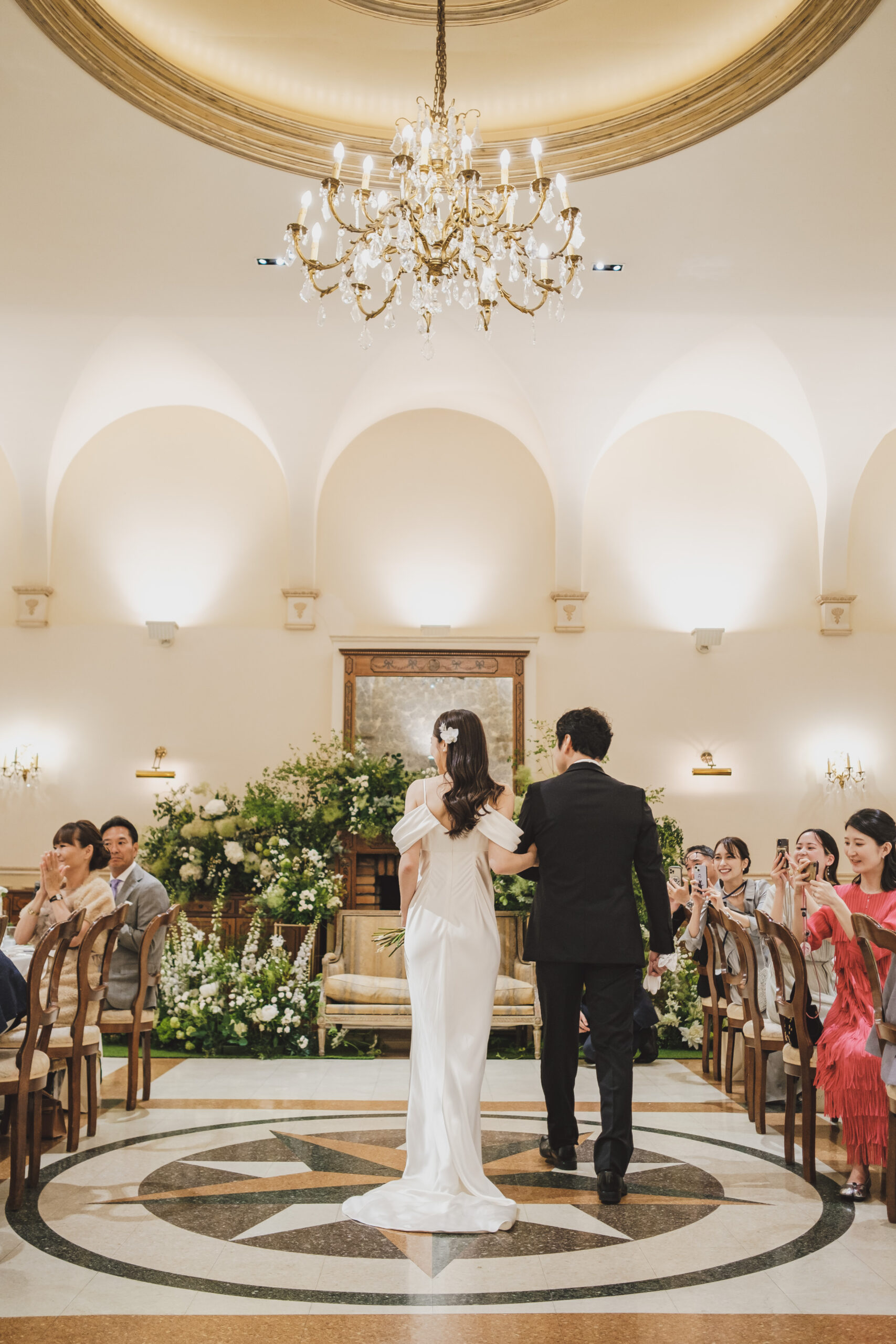 代官山のレストラン、リストランテASOの披露宴会場にトリートでお取り扱いのあるシンプルで洗練されたスレンダーラインのウェディングドレスを纏って入場されるご新婦様