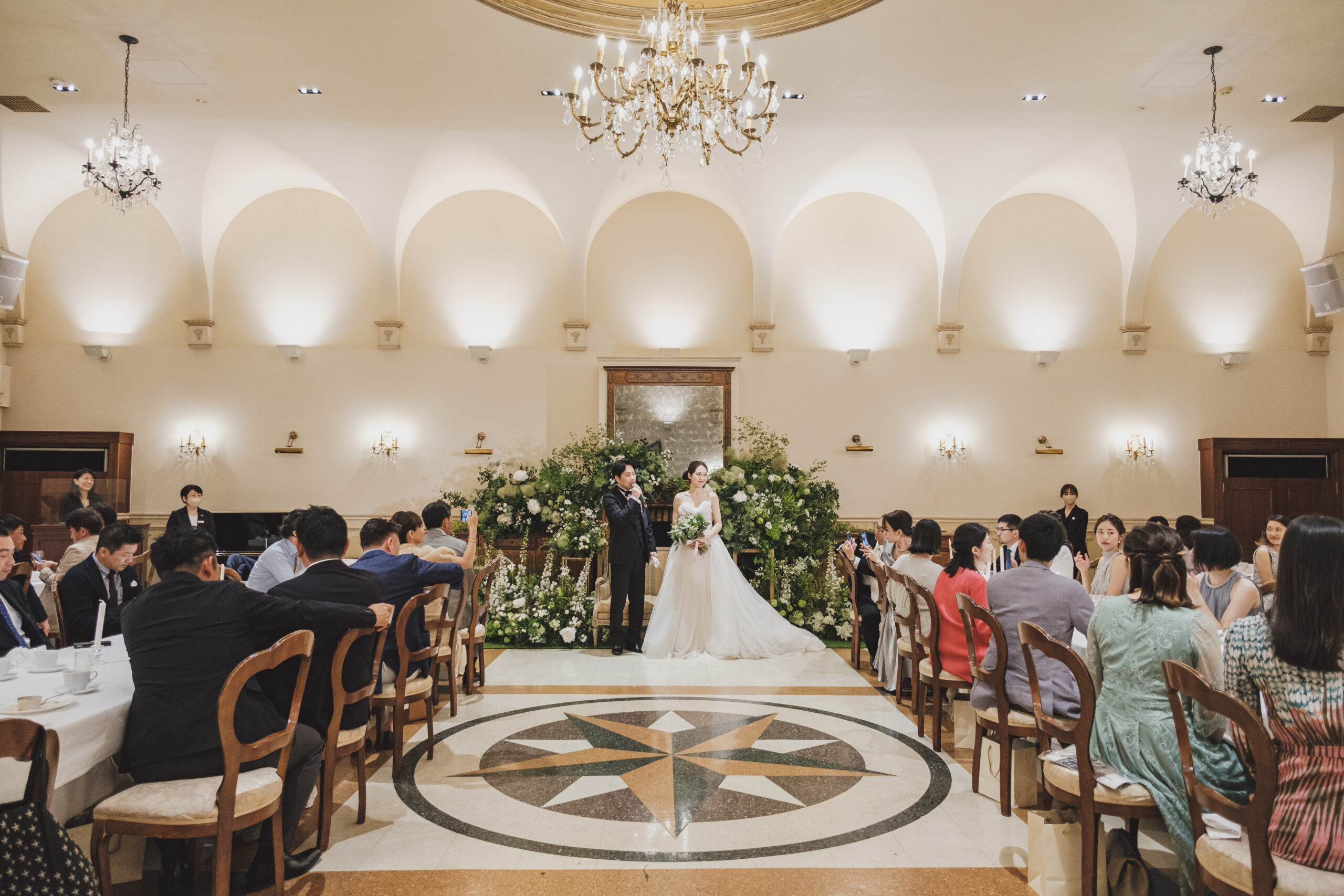 柔らかなブラッシュカラーのチュールをふんだんに使用したモニークルイリエのプリンセスラインのウェディングドレスをお色直しで纏うご新婦様とトリートジェントルマンのブラックのタキシードに身を包むご新郎様