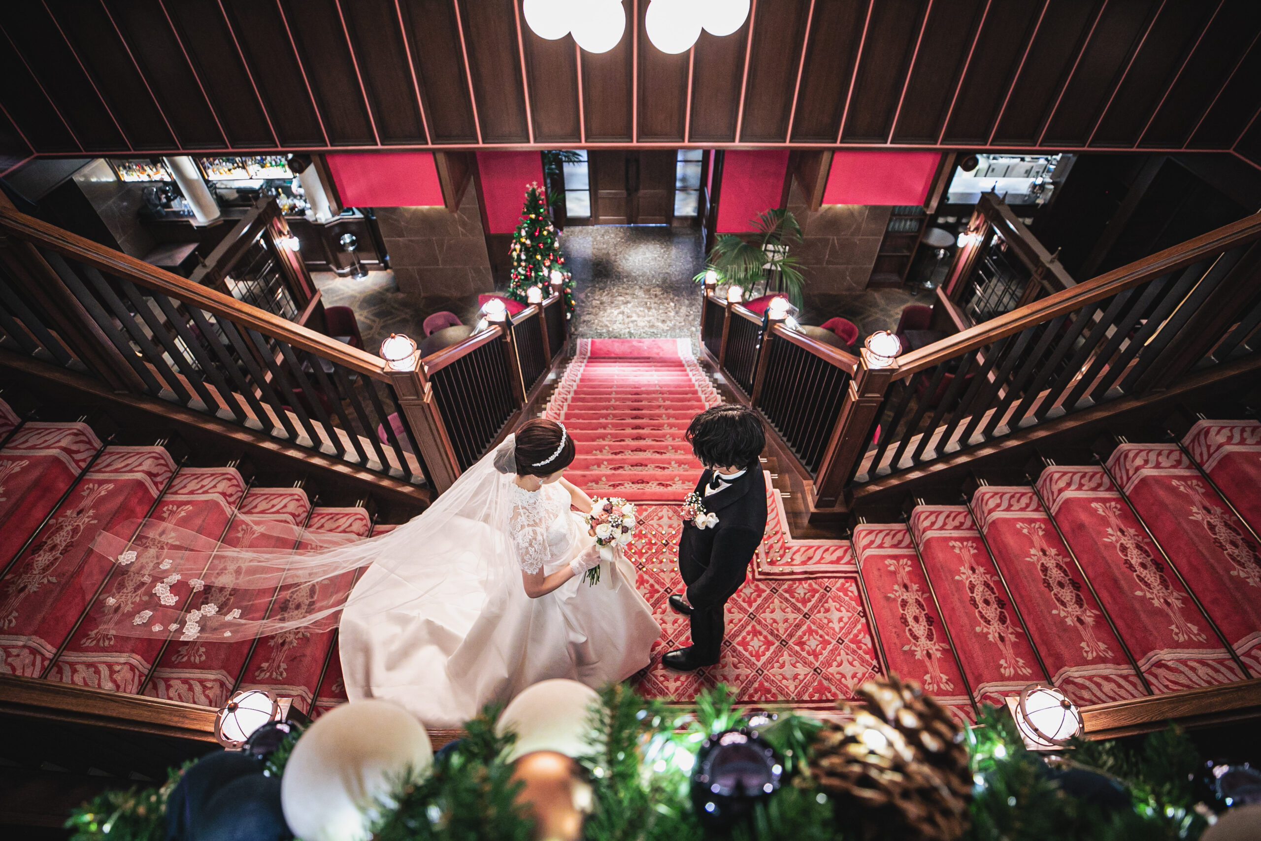 モダンで重厚感ある名古屋エリアのザ コンダーハウスの赤の大階段で行う、マークイングラムフォーヴァレンティーニのウェディングドレスを身に纏った花嫁のファーストミート