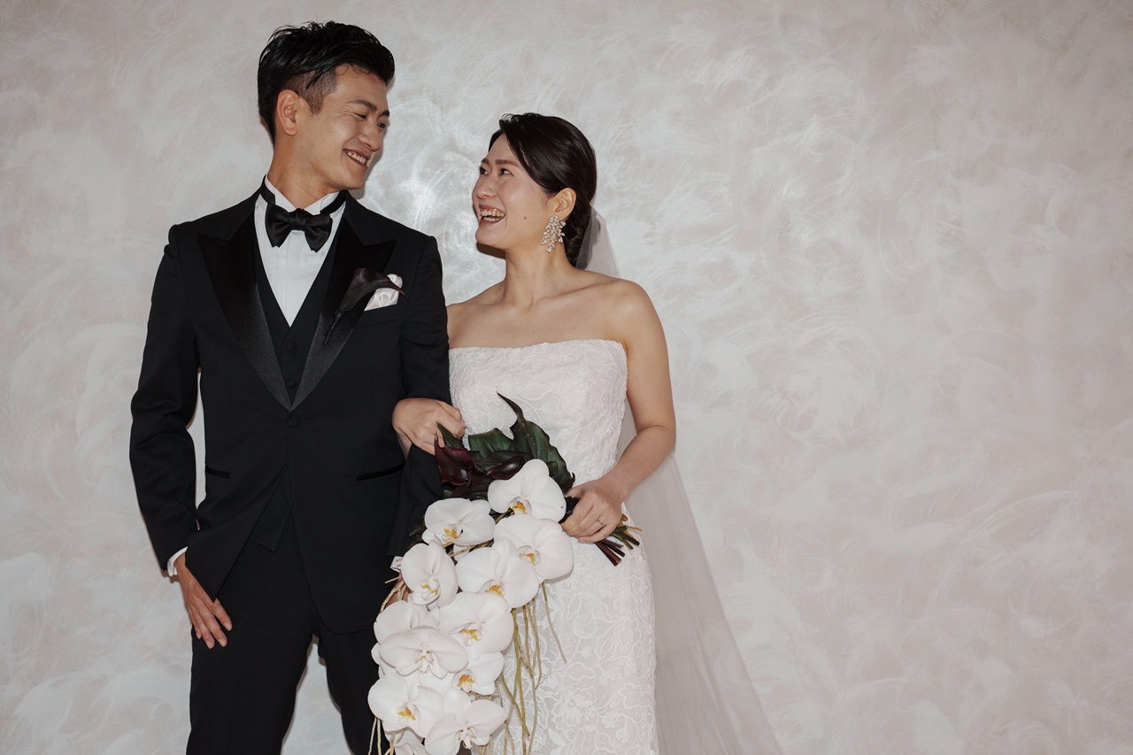 トリート ジェントルマンのブラックのピークドラペルのタキシード、Reem Acraのゴージャスなレンタルウェディングドレスの組み合わせは、お二人それぞれを引き立たせます