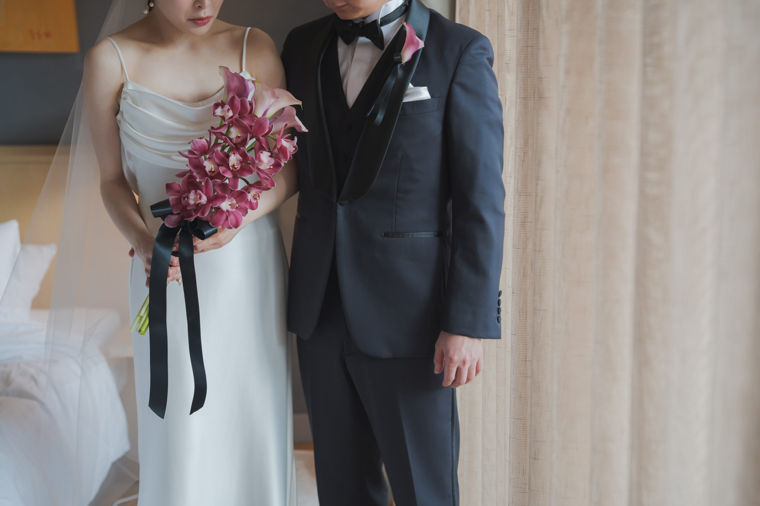 アムサーラのスレンダーラインのウェディングドレスと、ネイビーのタキシードで並んだコーディネートは流行りに流されないクラシカルなスタイルです