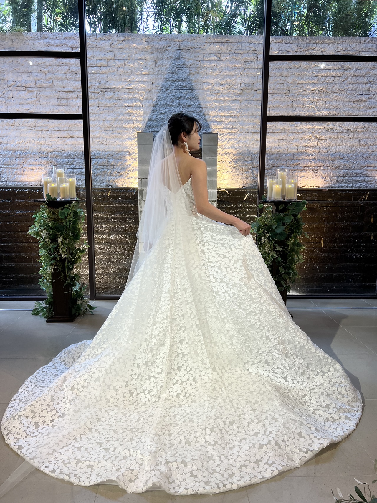 バックスタイルが映えるチャペルではボリュームのある裾をなびかせて、無地のロングベールを重ねた透明感ある華やかなスタイルを