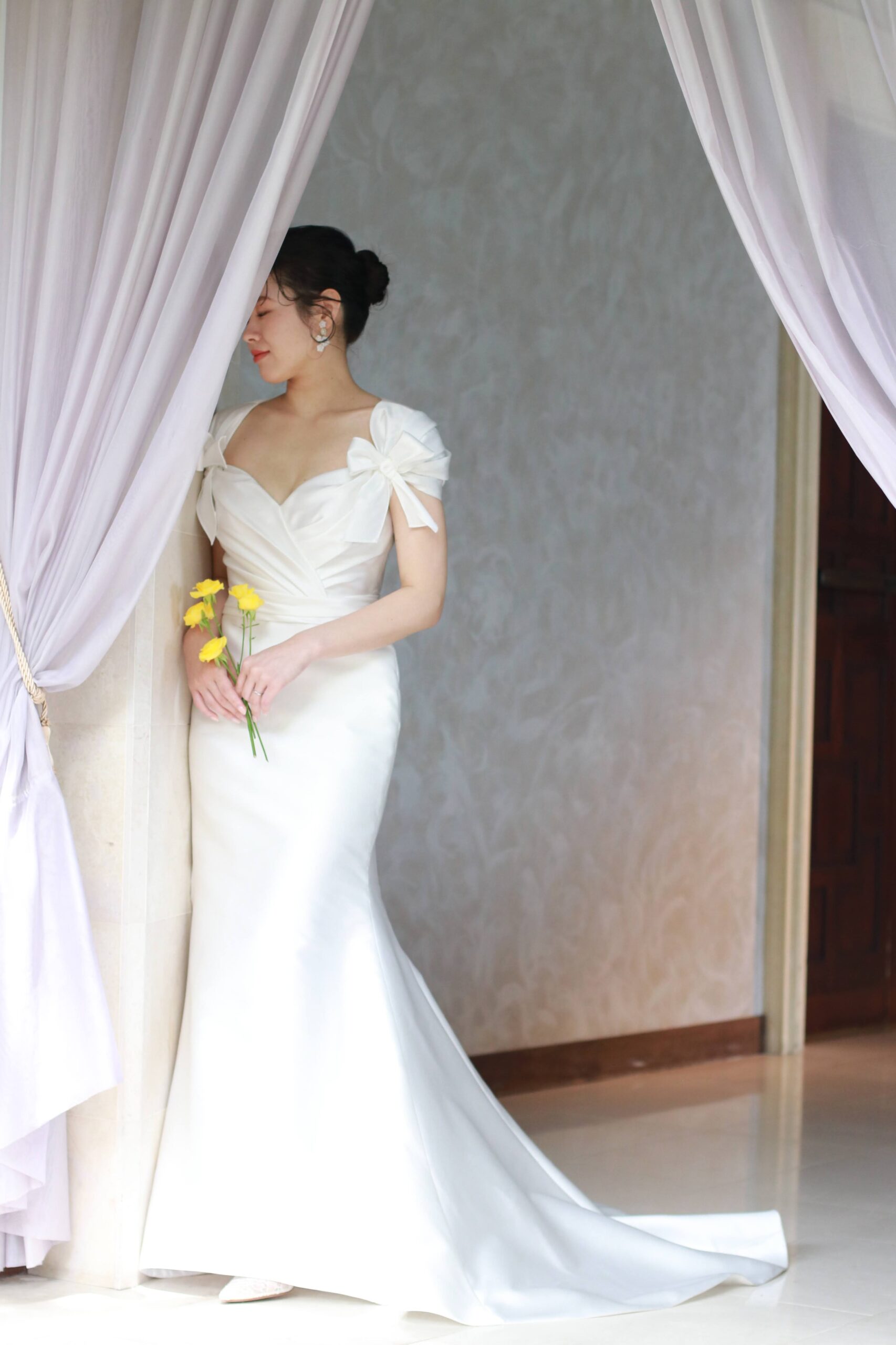 ザ ルイガンズの上質な空間にマッチする、リーム アクラの新作のマーメイドラインのウェディングドレスは、純白のシルクサテンとリボンモチーフが華やかで主役感のある一着です