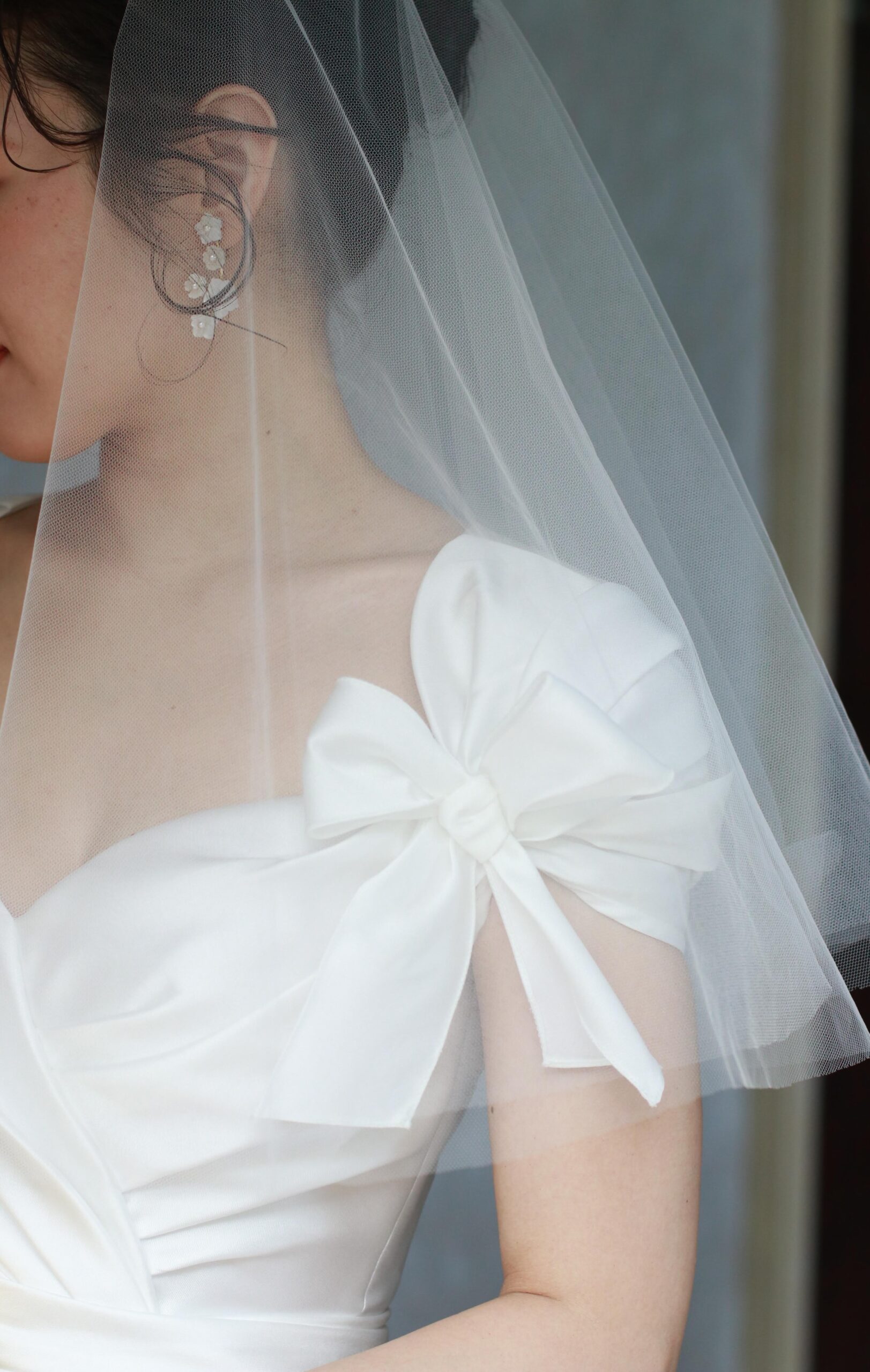 ジェニファー ベアの可愛い白のお花モチーフのイヤリングは、リボンモチーフのReem Acraのウェディングドレスにぴったりなでフェミニンなデザインです