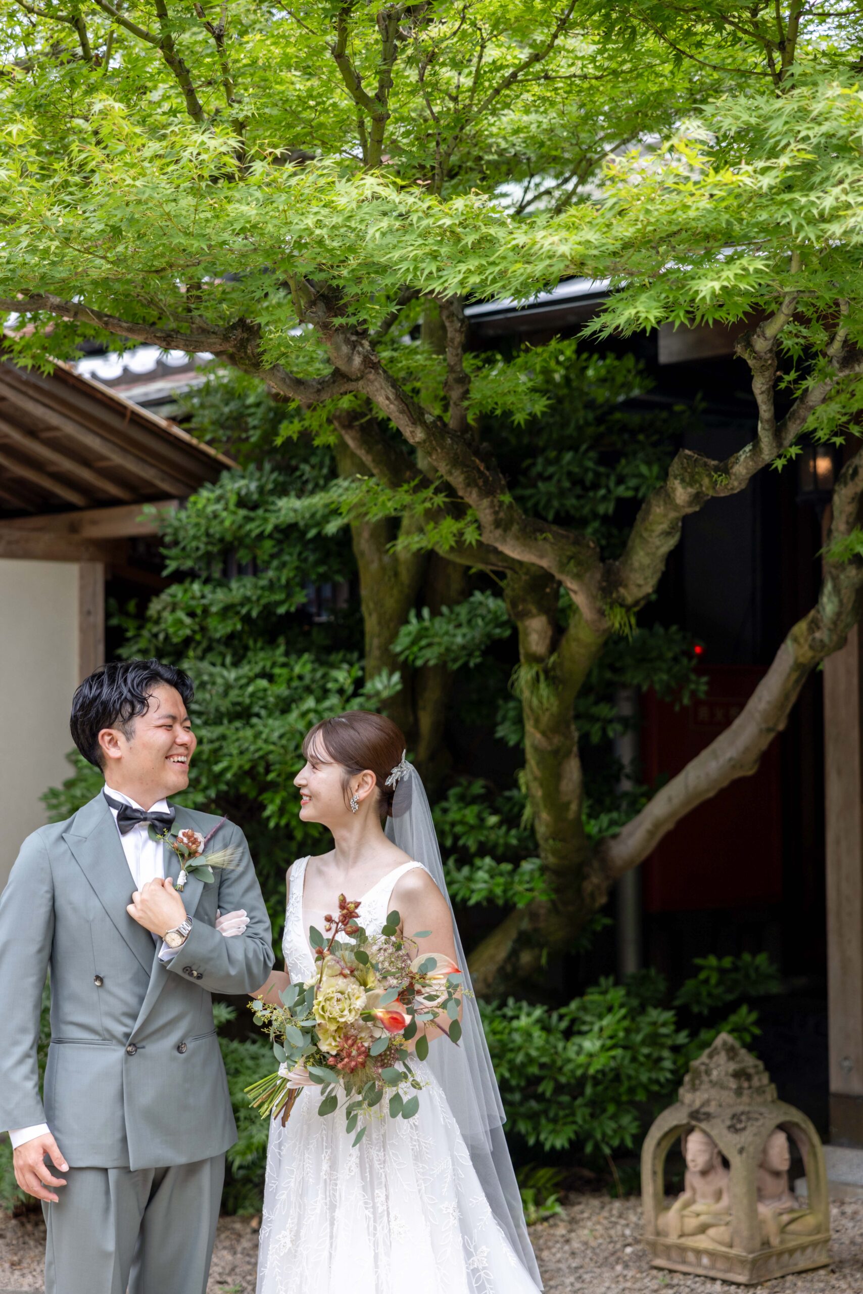 トリートドレッシングでしか出会えないネタドーヴァーのチュールのAラインのウェディングドレスを着ている新婦とグリーンのタキシード姿の新郎