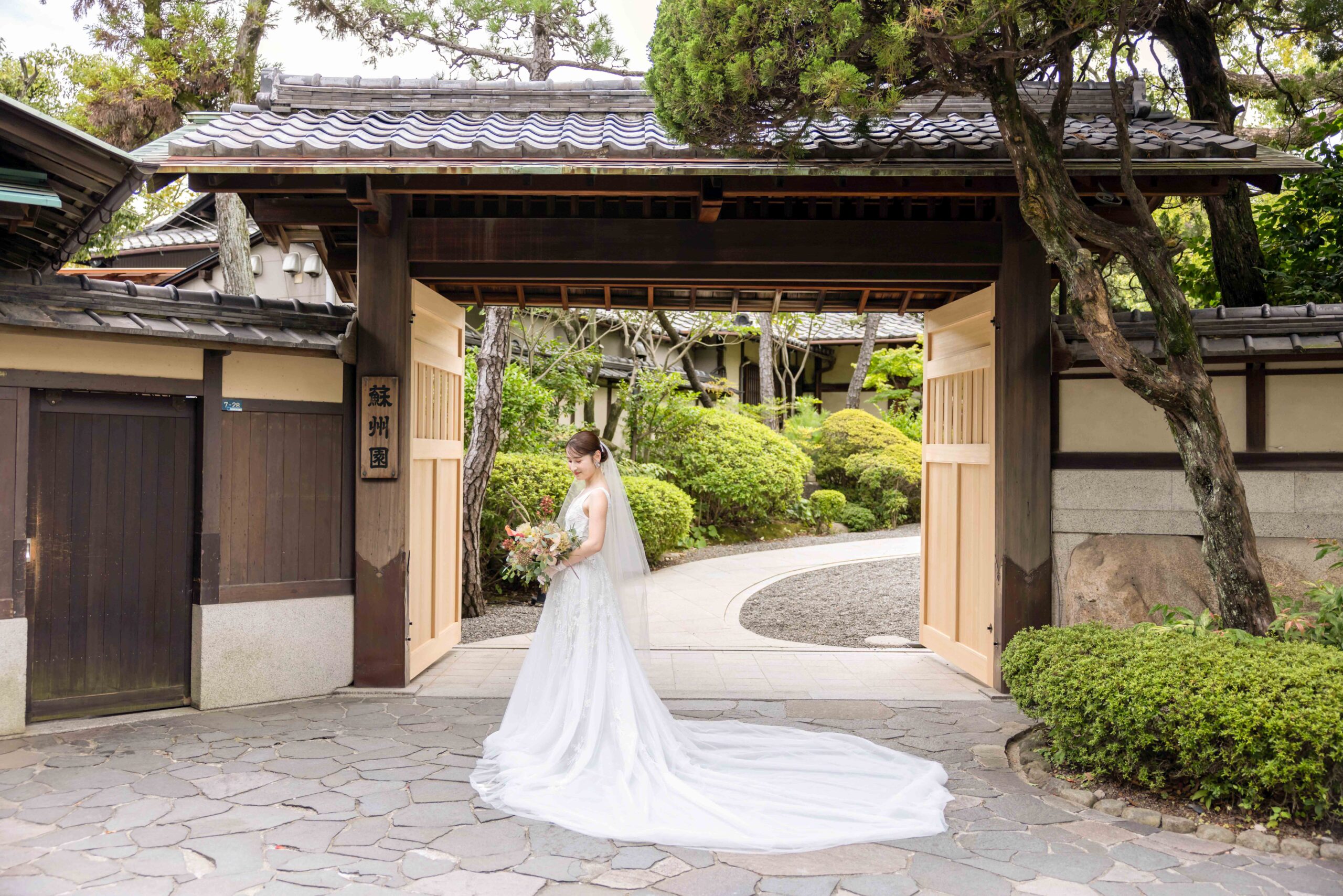 ザガーデンプレイス蘇州園の代表的なフォトスポットの大門前でネタドーヴァーのウェディングドレスを着る新婦様
