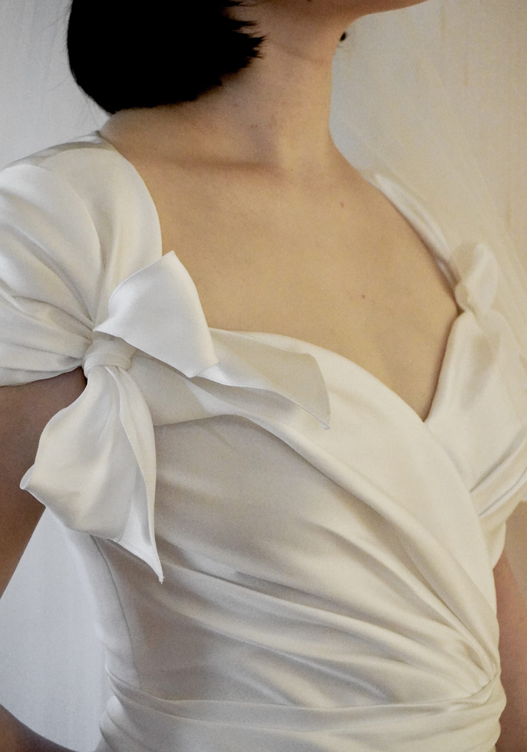 胸元のリボンモチーフがフェミニンでロマンティックなサテンのウェディングドレスで王道クラシカルなテイスト