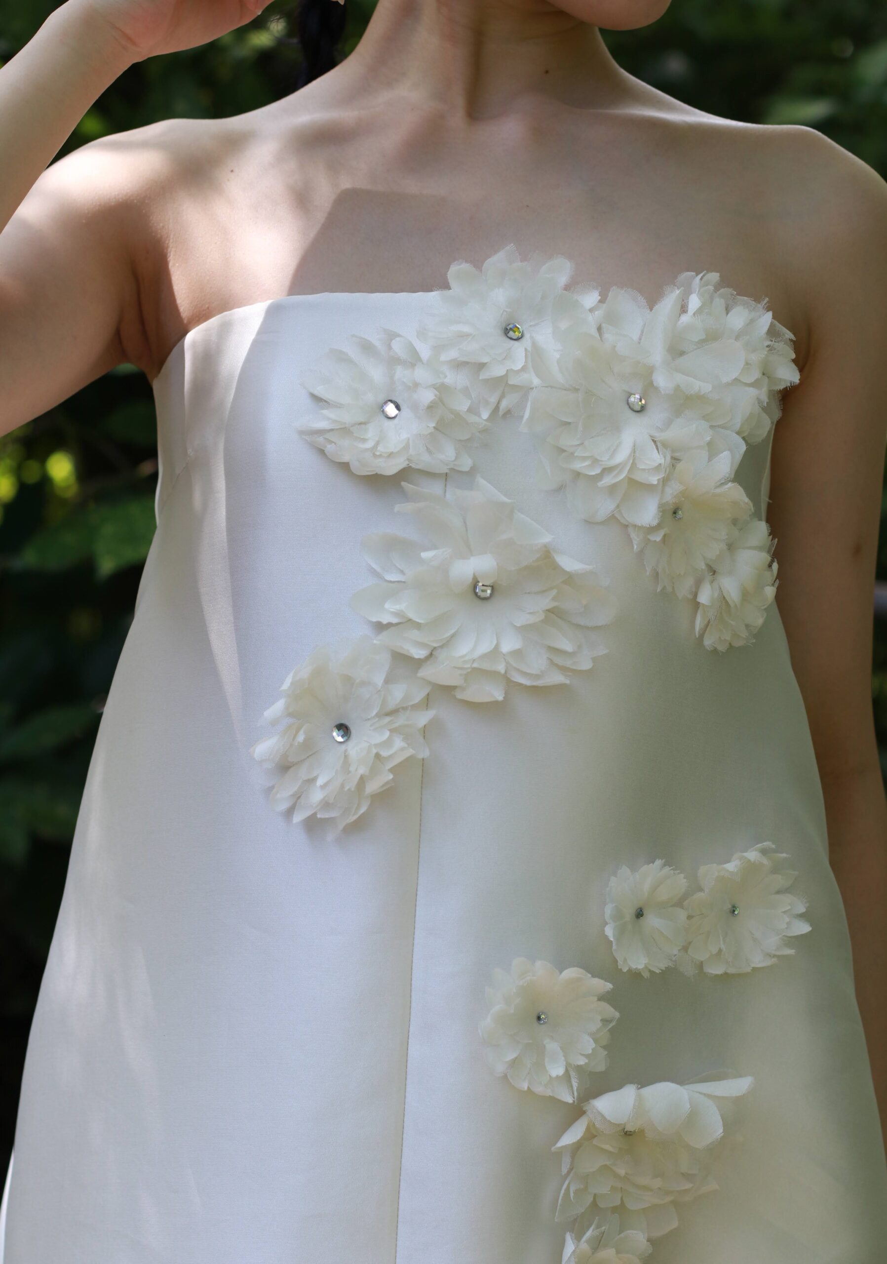 大阪のナチュラルな会場やモダンな披露宴会場におすすめしたい艶感ある上質な生地の上に3DのフラワーモチーフがあしらわれたAラインのウェディングドレス