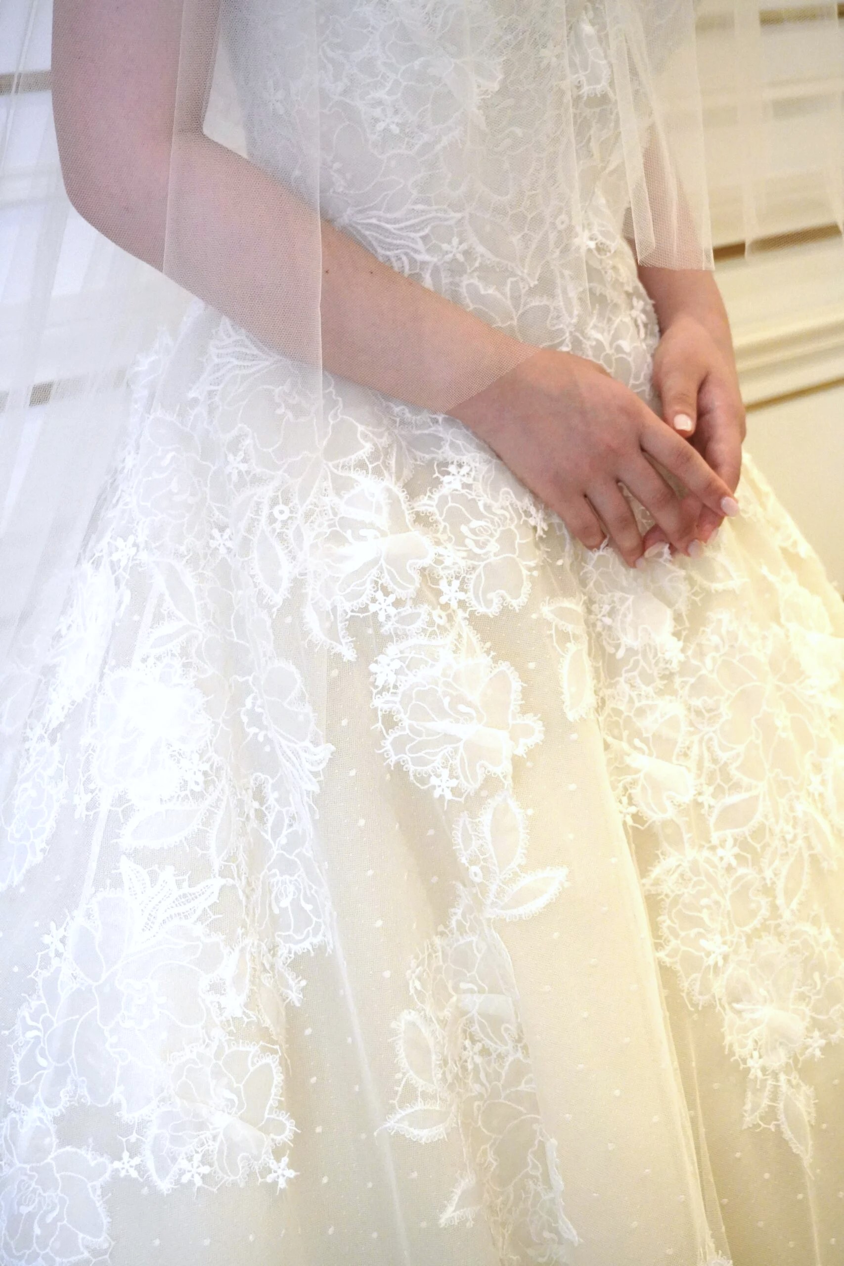 透明感溢れるチュールの上に、アップリケのようなフラワーレースがデザインされた上品なウェディングドレス