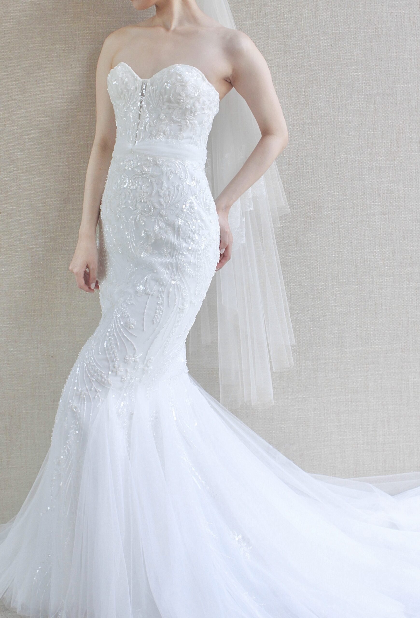 胸元のビジューのモダンで大人おしゃれなデザインから裾元に広がるチュールのトレーンが洗練された美しさを引き立たせるウェディングドレス